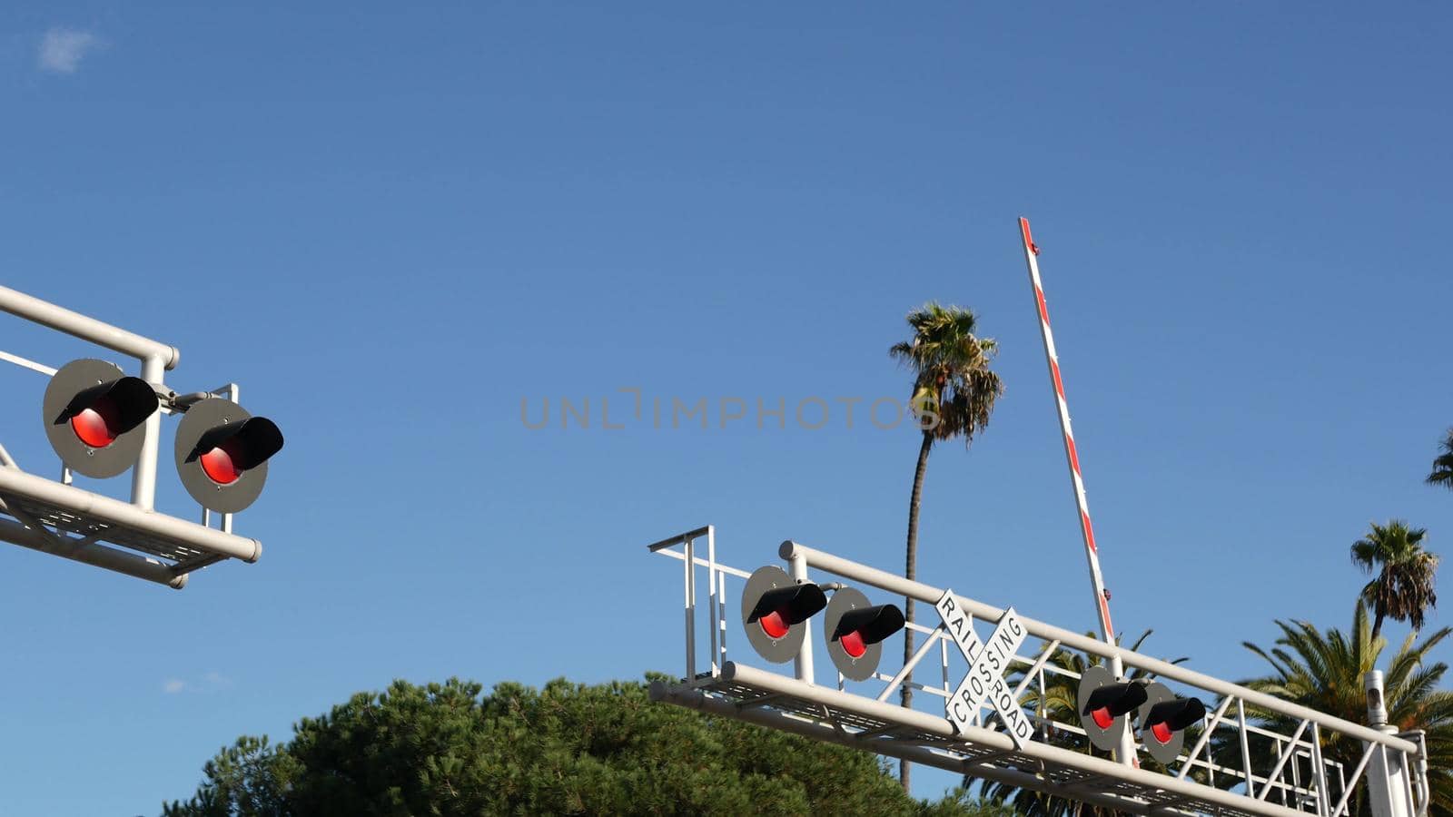 Level crossing warning signal in USA. Crossbuck notice and red traffic light on rail road intersection in California. Railway transportation safety symbol. Caution sign about hazard and train track.