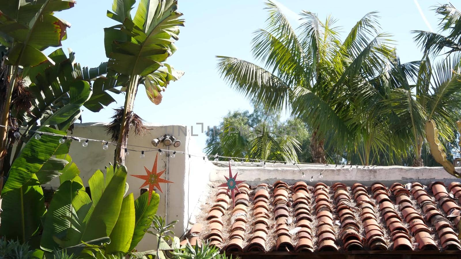 Mexican colonial style suburban, hispanic house exterior, green lush garden, San Diego, California USA. Mediterranean terracotta ceramic clay tile on roof. Rustic spanish tiled rooftop. Rural details.