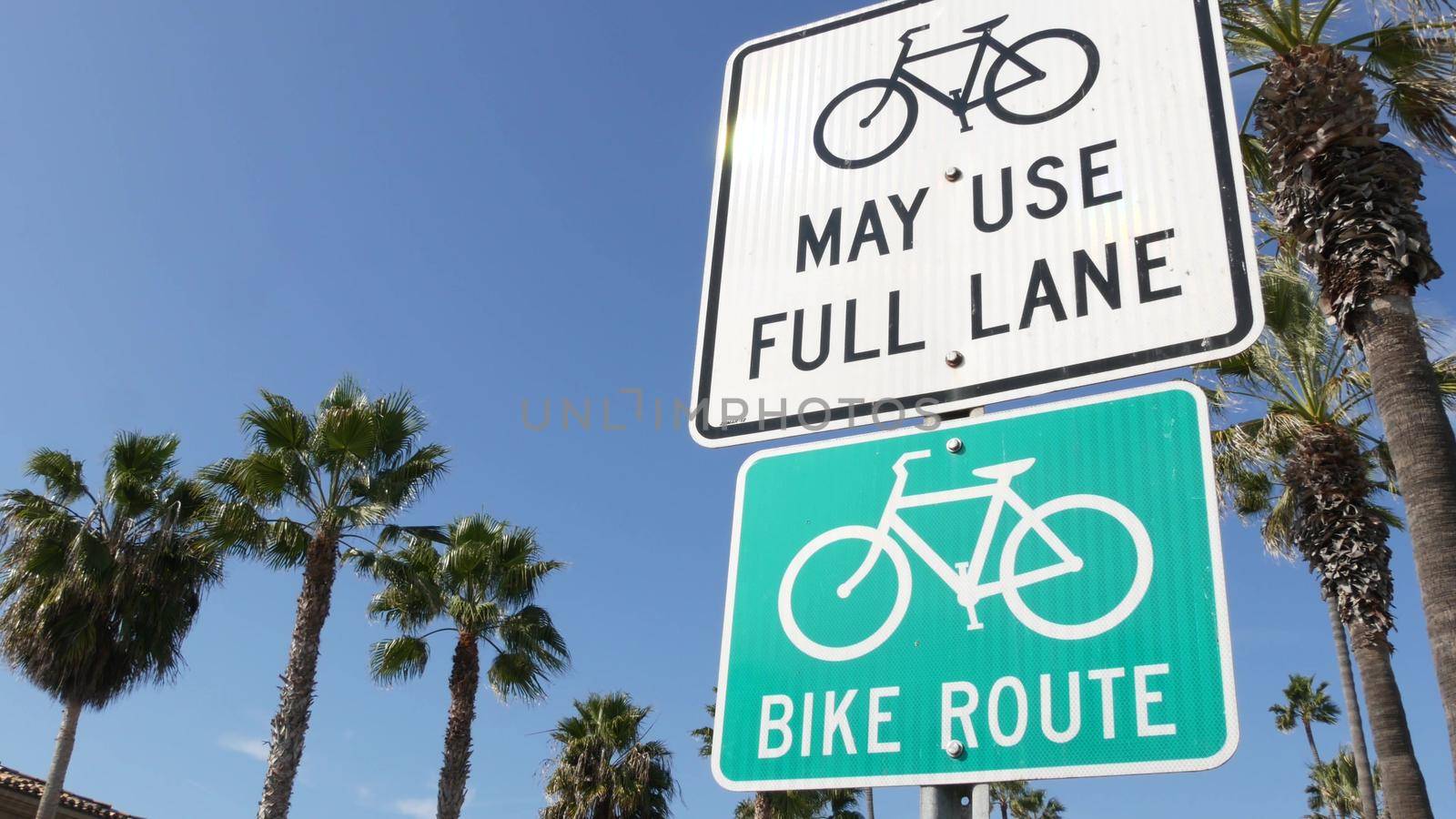 Bike Route green road sign in California, USA. Bicycle lane singpost. Bikeway in Oceanside pacific tourist resort. Cycleway signboard and palm. Healthy lifestyle, recreation and safety cycling symbol.
