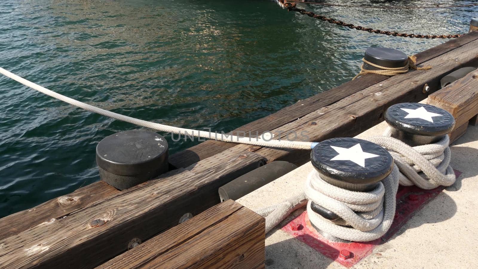 Tied rope knot on metallic bollard with stars, seafaring port of San Diego, California. Nautical ship moored in dock. Cable tie fixed on wharf. Symbol of navy marine sailing and naval fleet, USA flag by DogoraSun