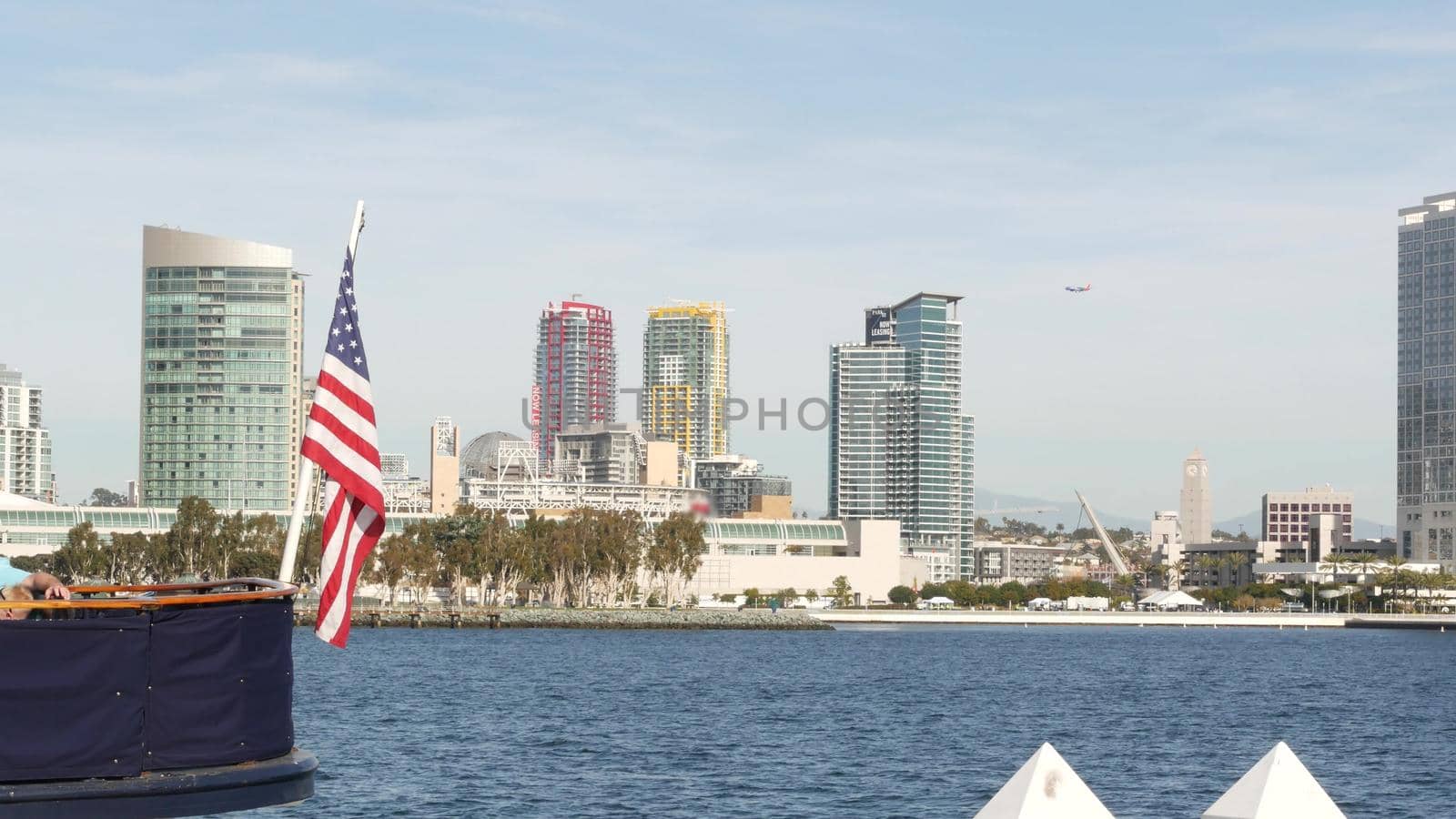 Metropolis urban skyline, highrise skyscrapers of city downtown, San Diego Bay, California USA. Waterfront buildings near pacific ocean harbour. Star-Spangled Banner, Old Glory national flag waving.