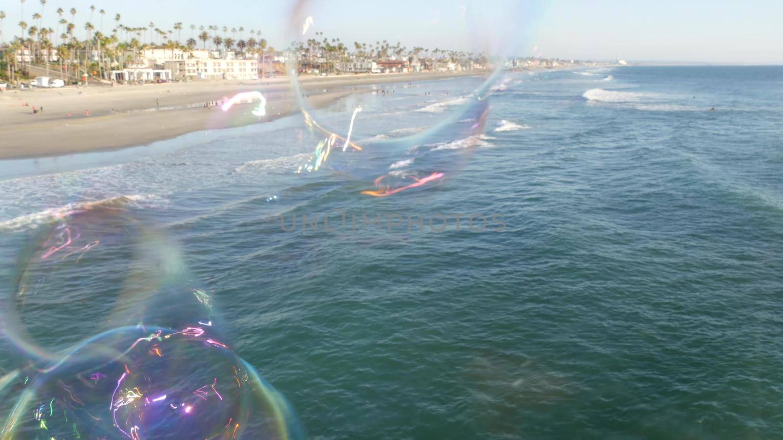 Soap bubbles on pier in California, blurred summertime seamless looped background. Creative romantic metaphor, concept of dreaming, happiness and magic. Abstract symbol of childhood, fantasy, freedom.