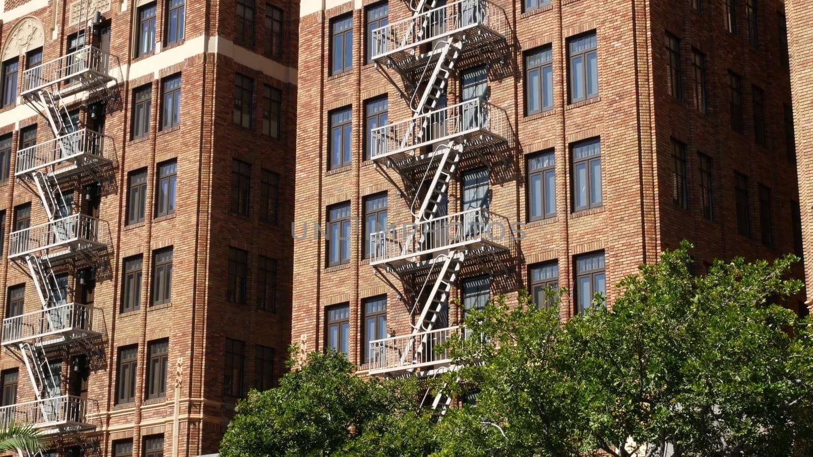 Fire escape ladder outside residential brick building in San Diego city, USA. Typical New York style emergency exit for safe evacuation. Classic retro house exterior as symbol of real estate property.