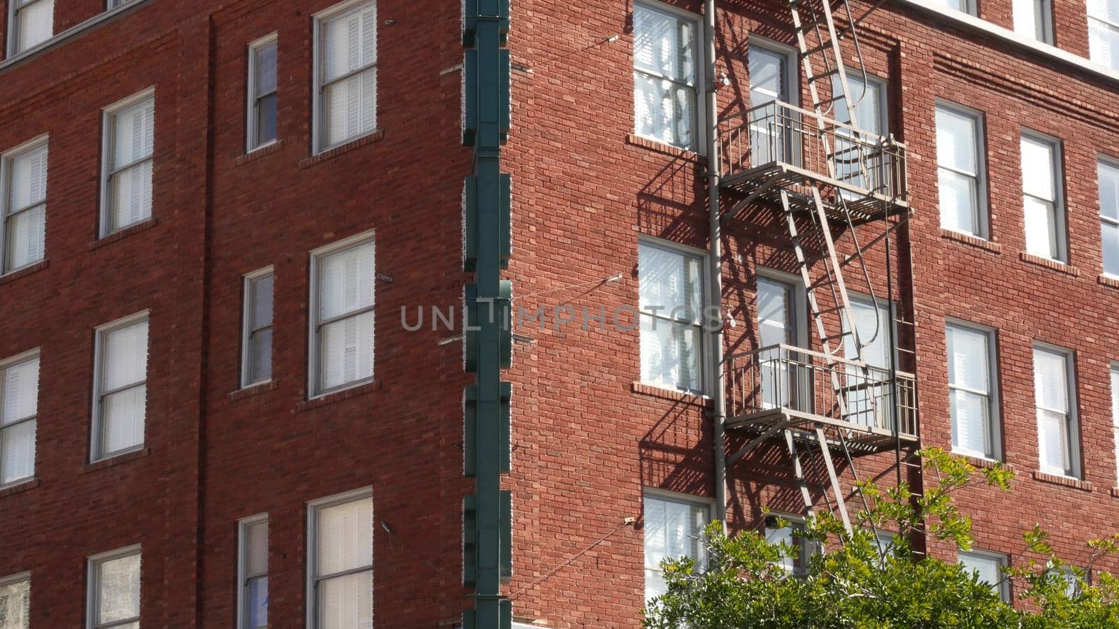 Fire escape ladder outside residential brick building in San Diego city, USA. Typical New York style emergency exit for safe evacuation. Classic retro house exterior as symbol of real estate property.