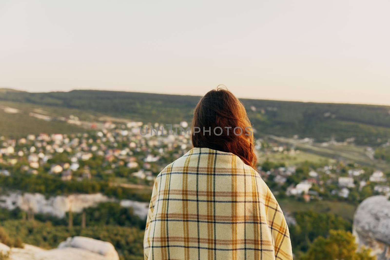 woman with a plaid on her shoulders in nature and buildings in the background by SHOTPRIME