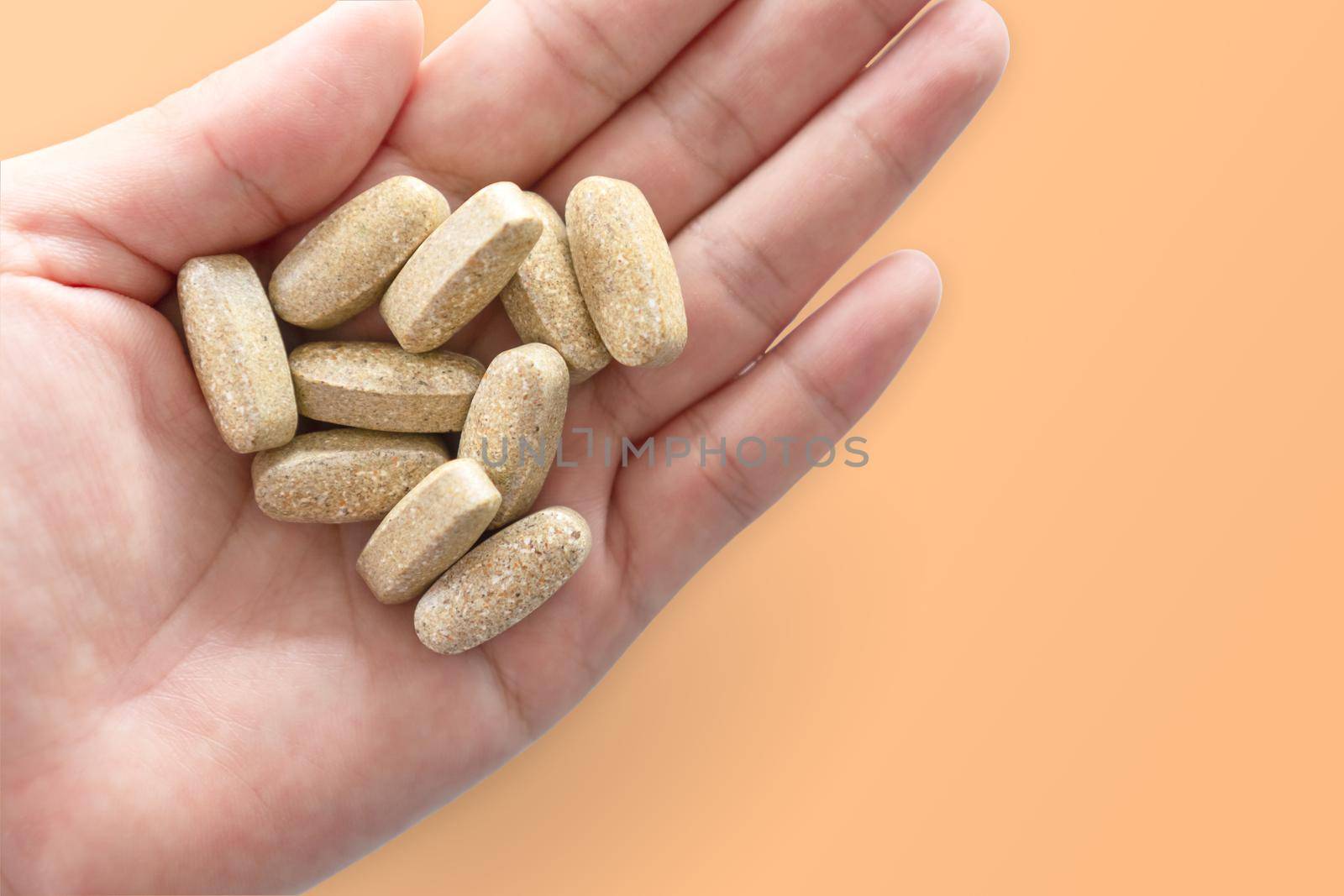 Top view of alternative organic medicine or herbal viatmin supplement capsule tablet on woman hand with copyspace background. Concept of healthy eating. by Suwant