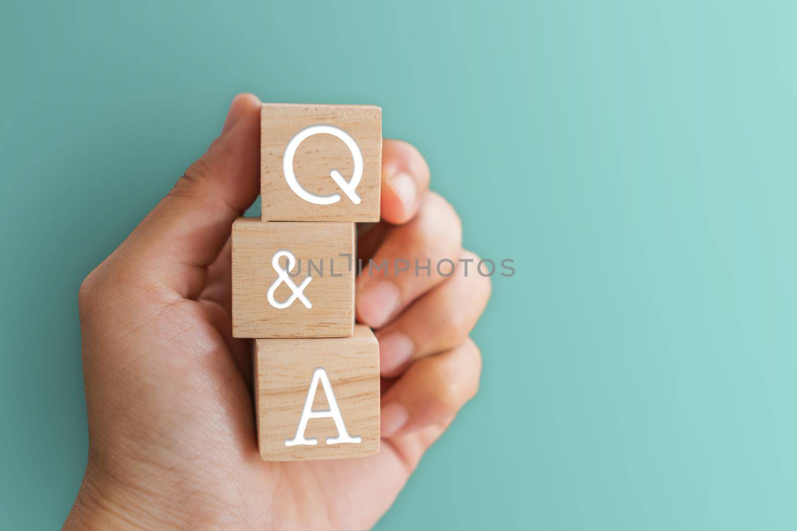 Q and A alphabet on wooden cube in hand hold with background. Question and answer meaning. by Suwant