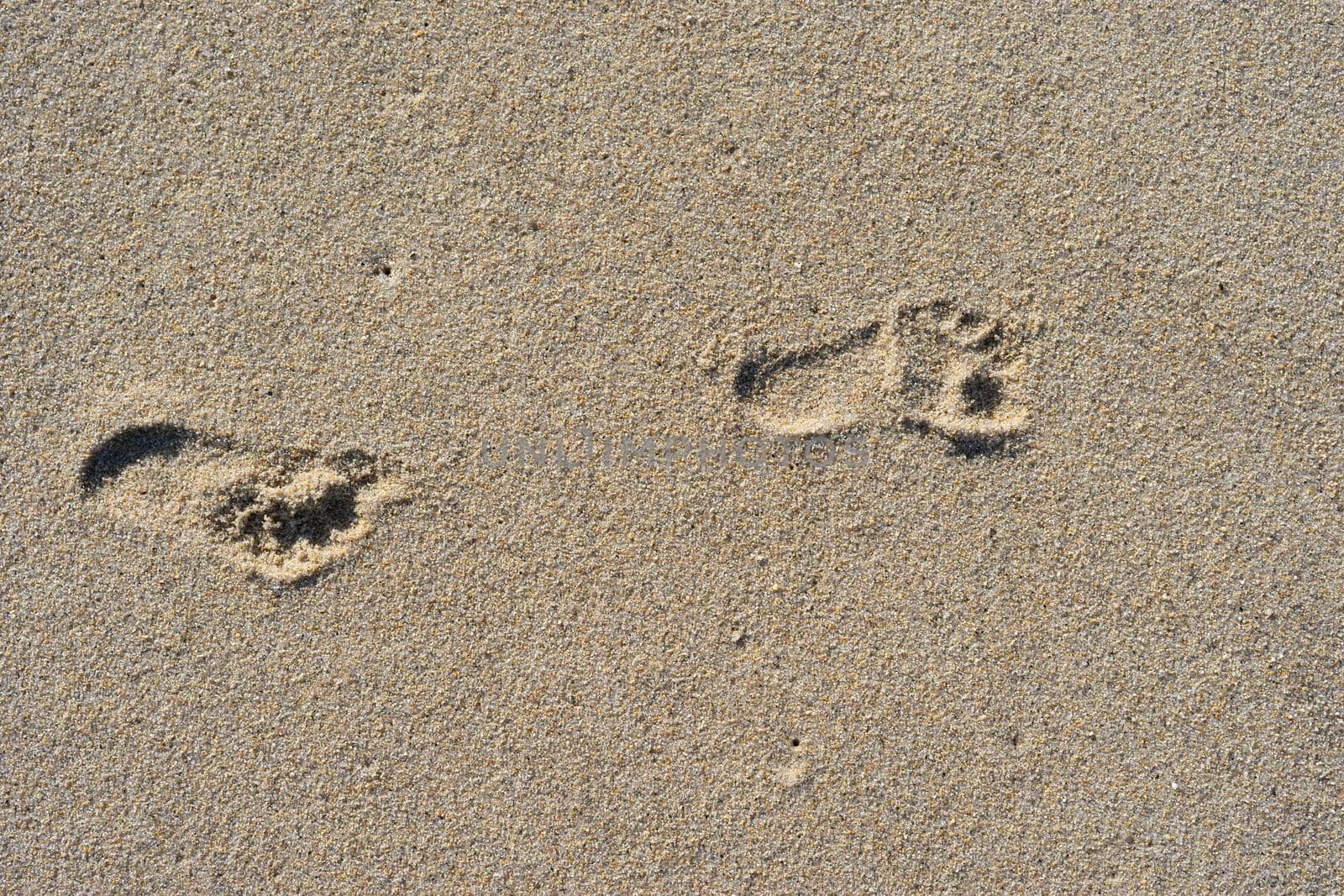 Natural background of sand with the prints of human feet