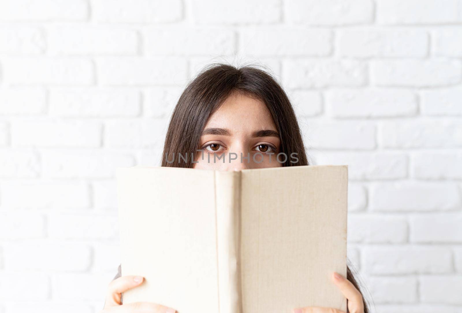 Close up of woman holding an opened book in front of her face