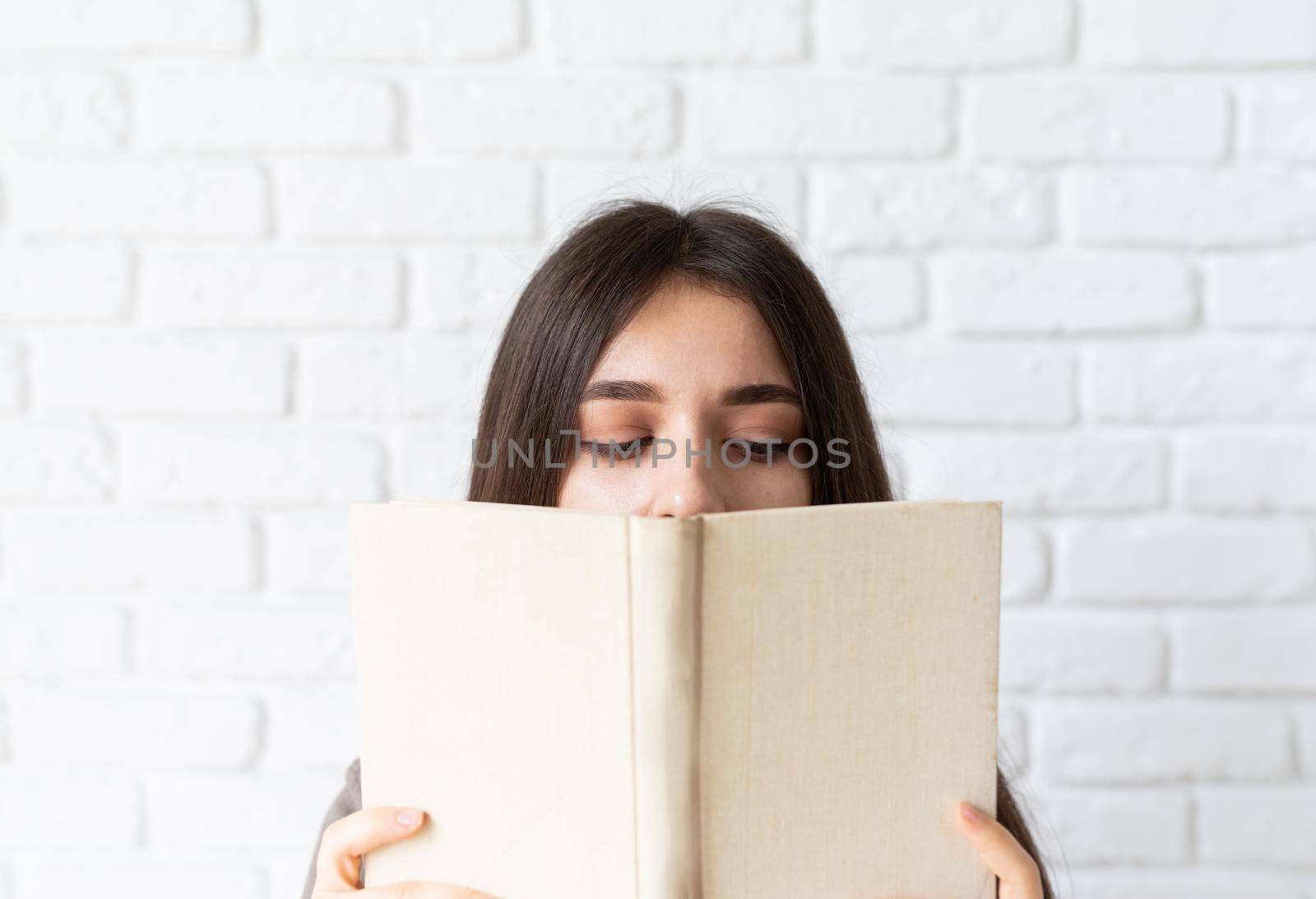 Close up of woman holding an opened book in front of her face