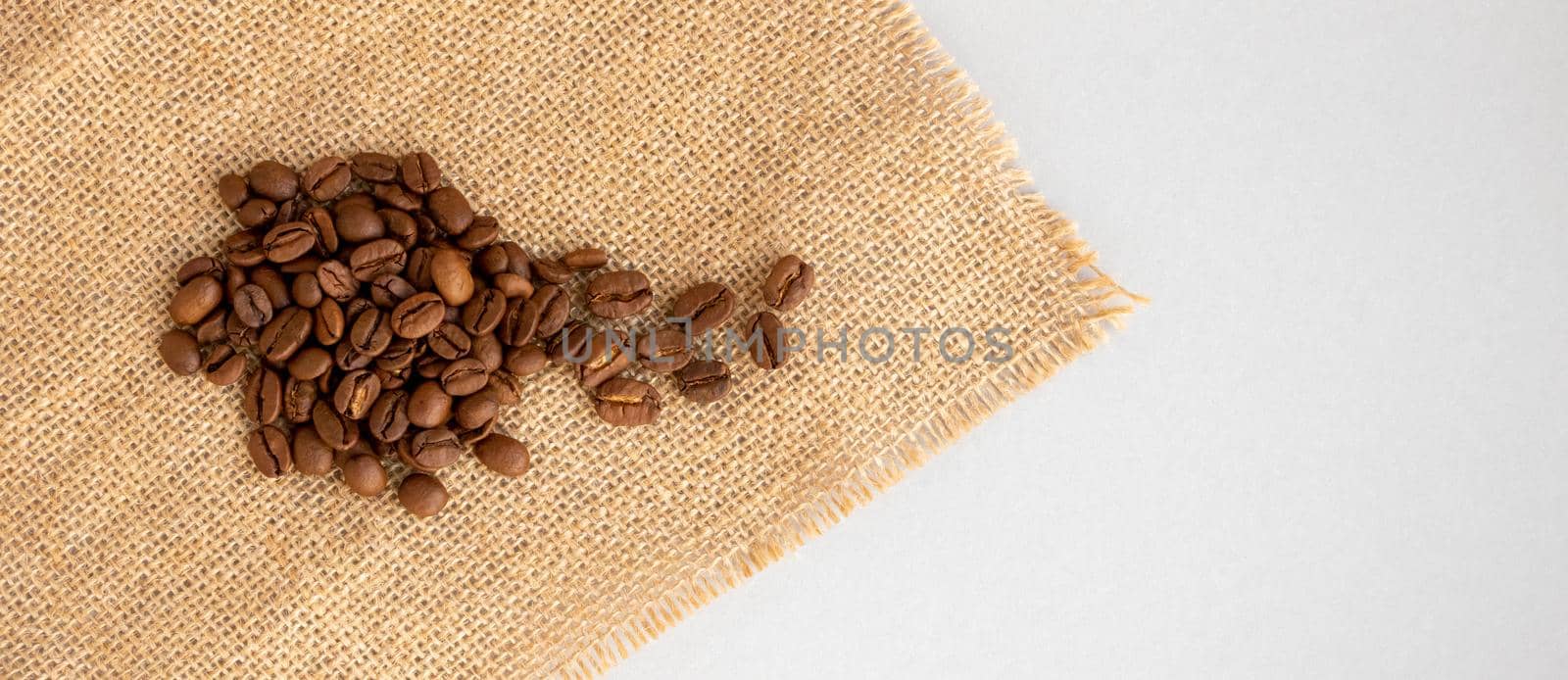 Coffee beans and burlap lie on a gray background.