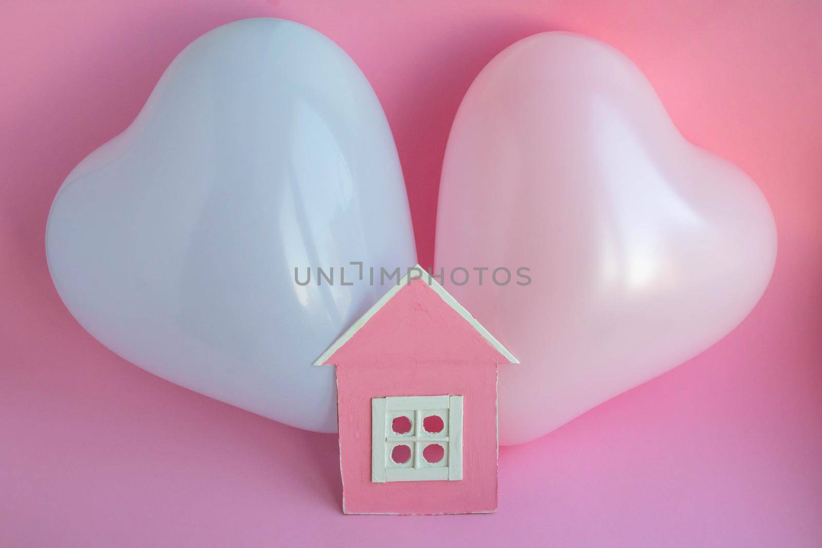 Two balloons and a pink cardboard house on a pink background. Family history in symbols.
