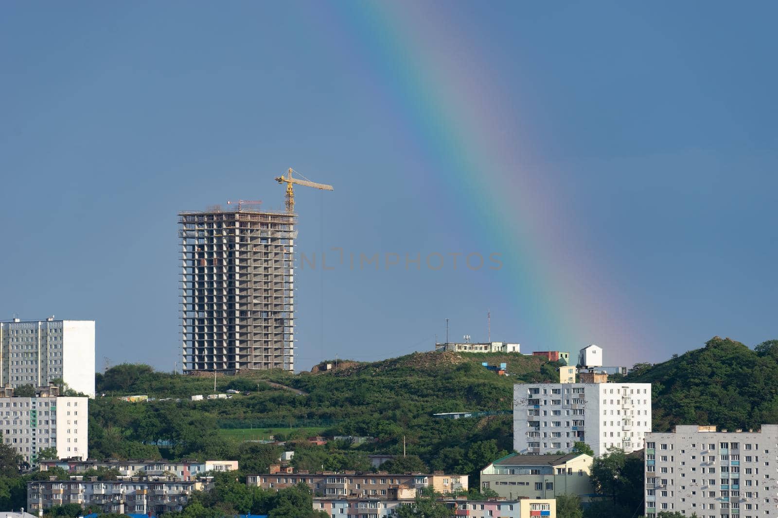 Urban landscape with a rainbow on the sky background. Vladivostok, Russia