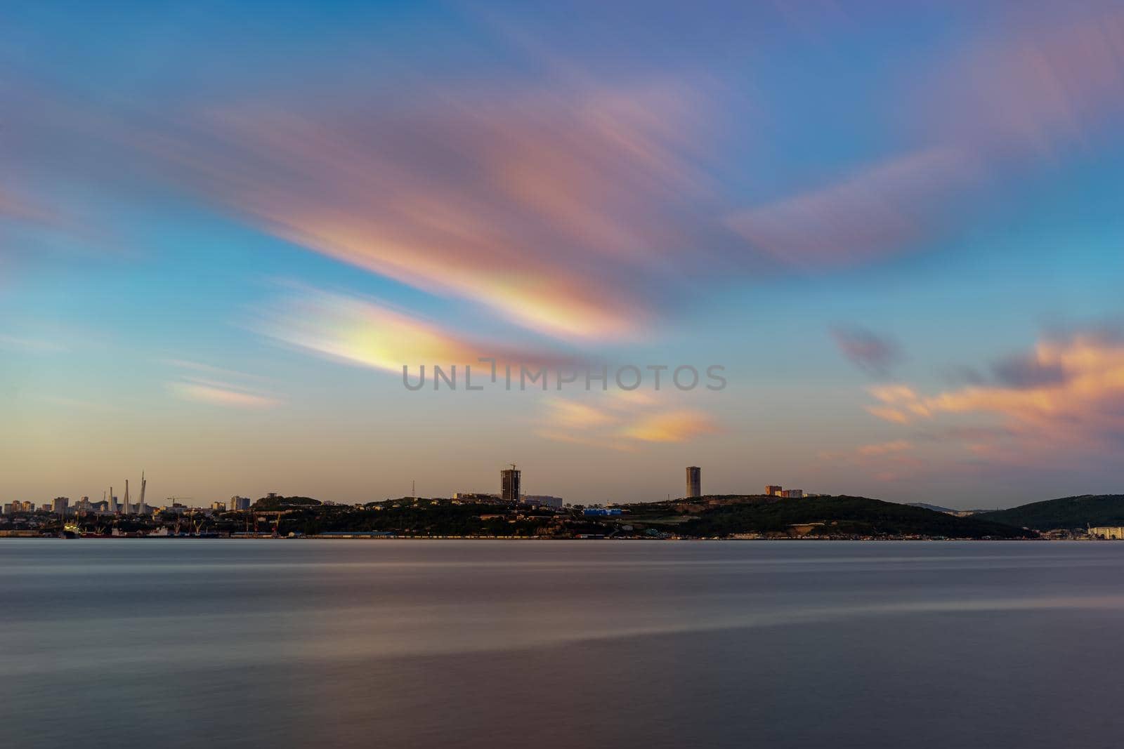 Seascape overlooking the city on the horizon. Charged with long videjko. Beautiful sunset in soft pastel colors. Vladivostok, Russia