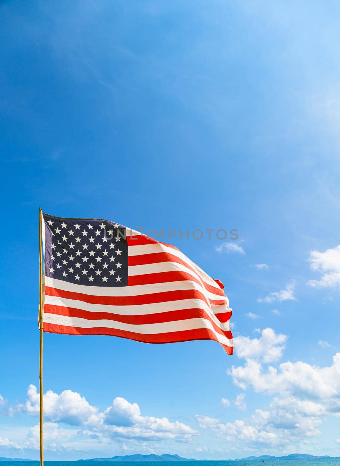 Flag of United States of America (USA) waving in the wind with blue sky and cloud on a sunny day