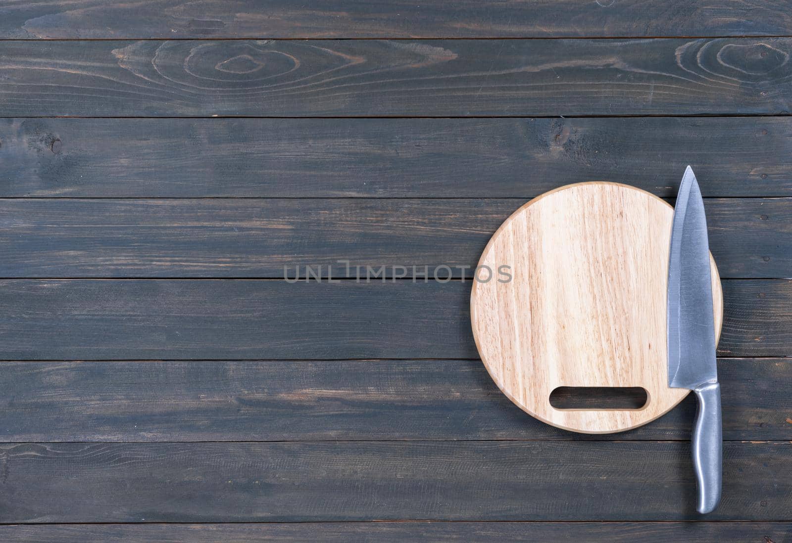 Close up kitchen knife and round cutting board on a wooden table