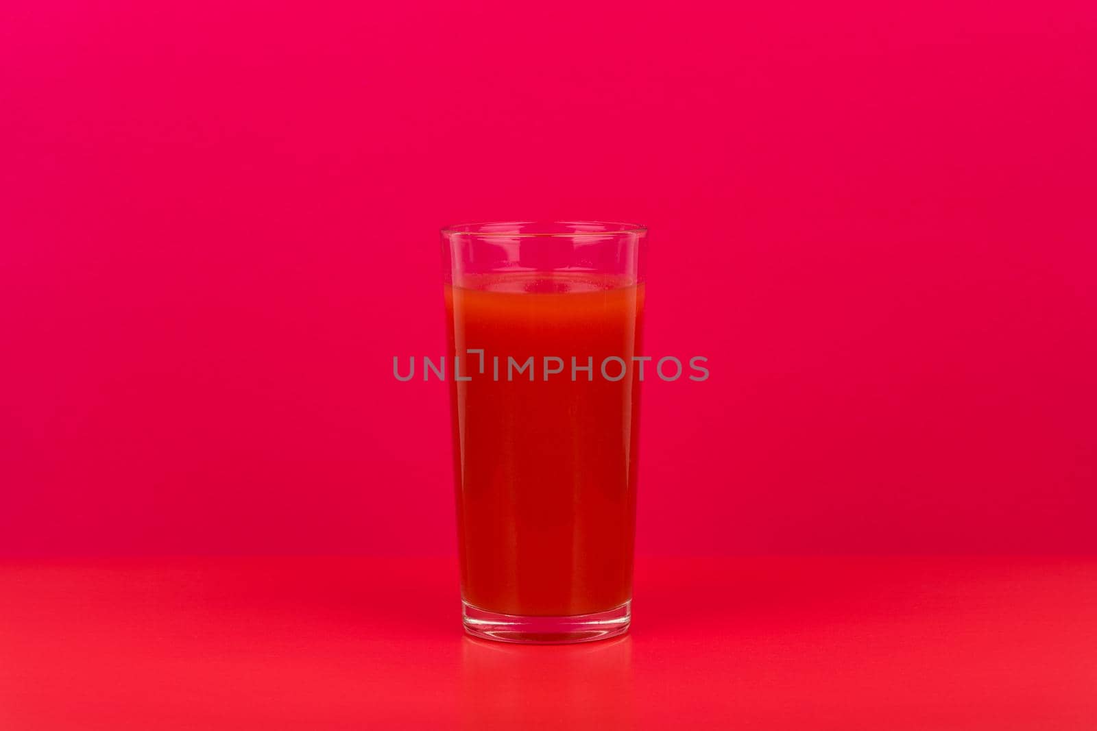 Glass of tomato juice on red table against pink background with copy space. Concept of vegan food and healthy eating by Senorina_Irina