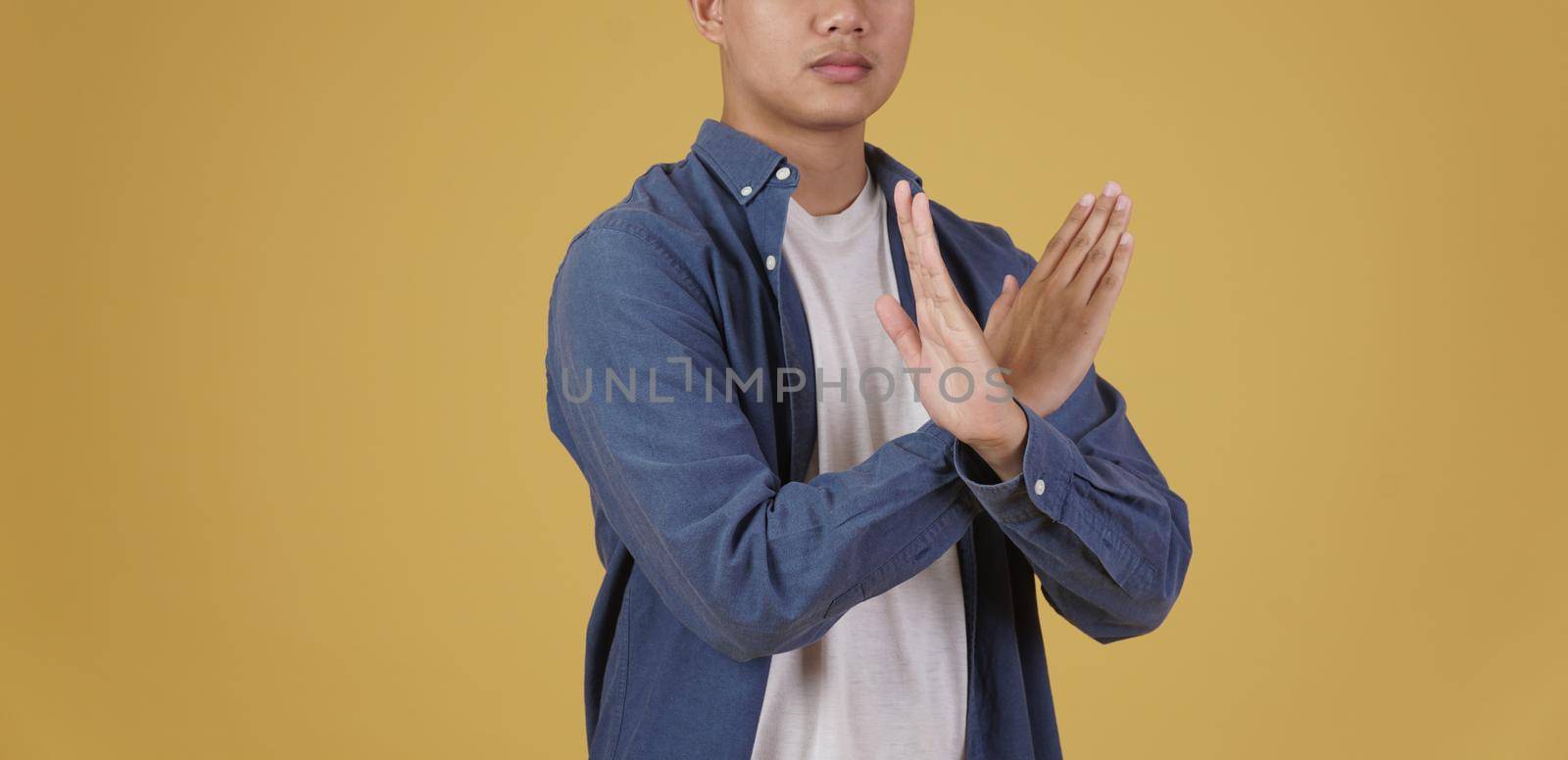 portrait of handsome young asian man dressed casually crossing arms in negative rejection or no expression isolated on yellow background by pp99
