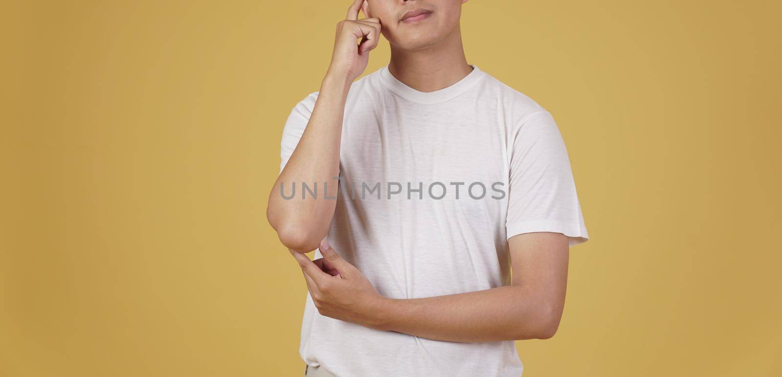 portrait of thoughtful young asian man dressed casually thinking doubting wondering isolated on yellow background by pp99