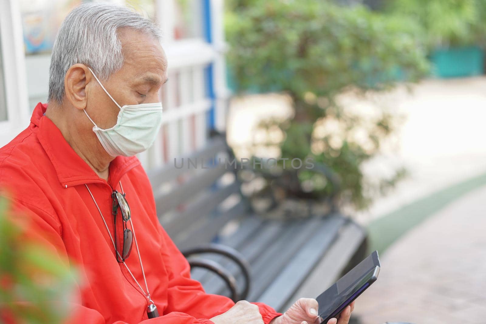 asian old elder senior man wearing face mask elderly using mobile smart phone cellphone. mature retirement lifestyle by pp99