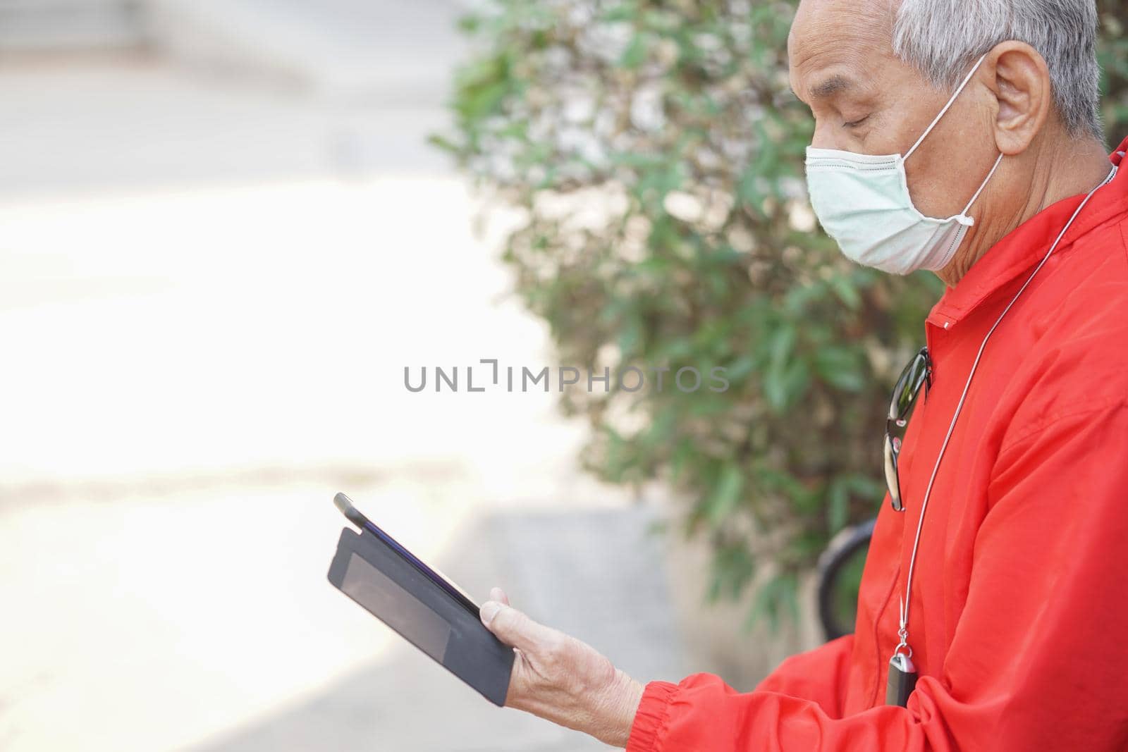 asian old elder senior man wearing face mask elderly using mobile smart phone cellphone. mature retirement lifestyle by pp99