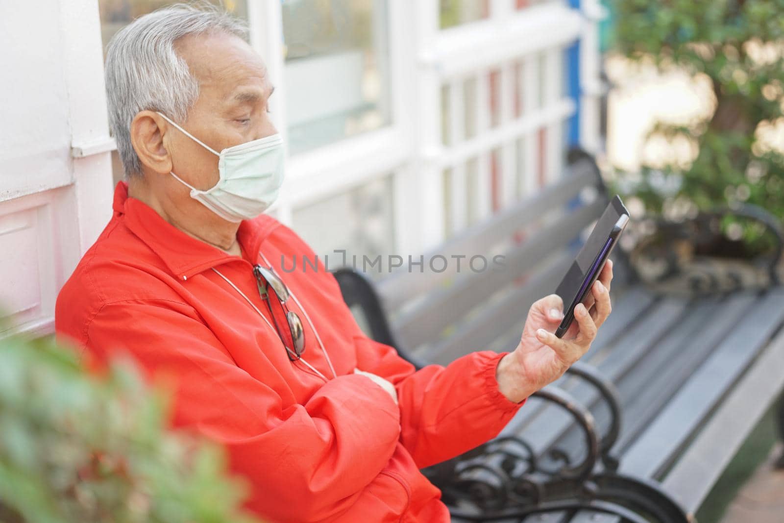 asian old elder senior man elderly male wearing face mask using mobile smart phone cellphone outdoor. mature retirement lifestyle