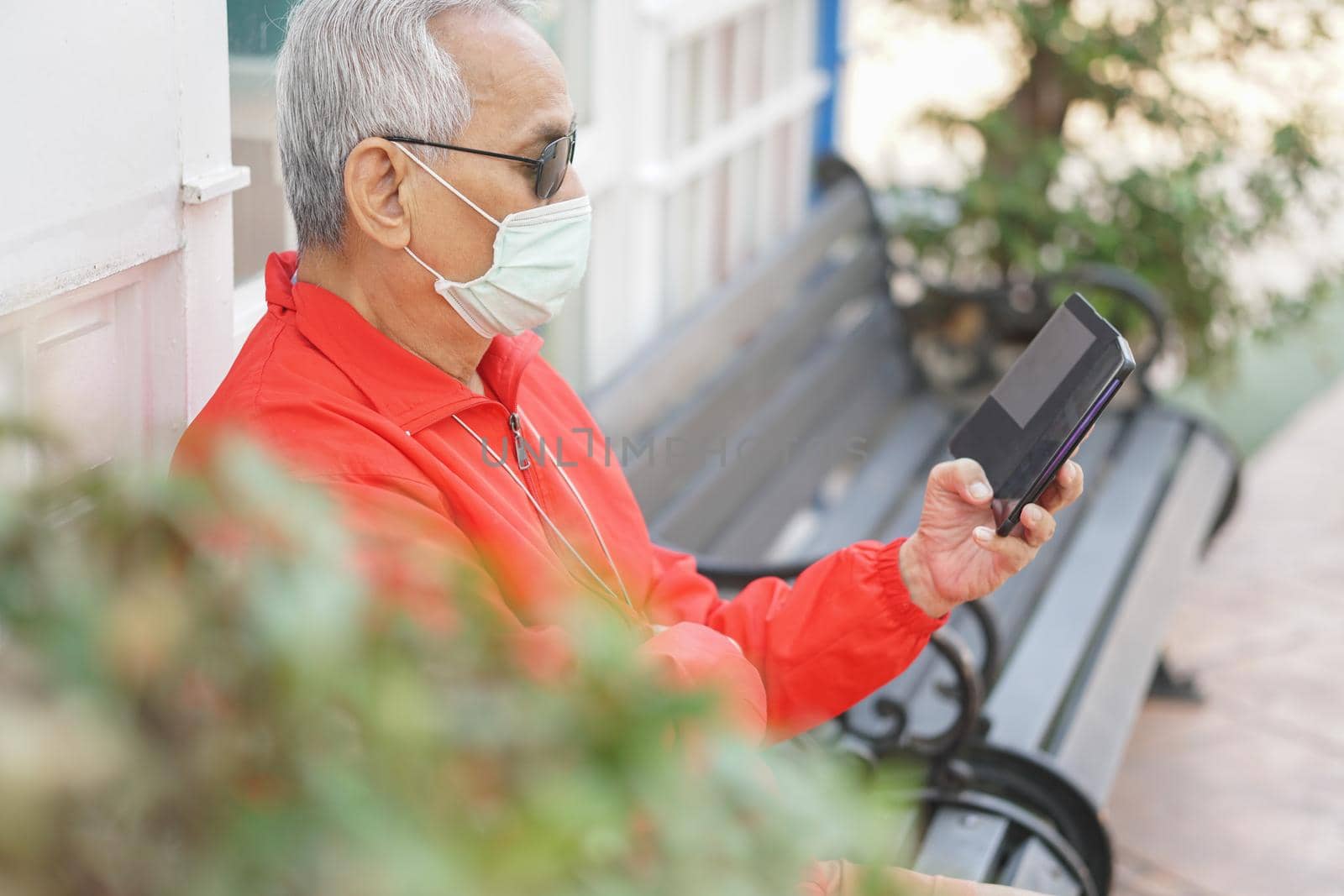 asian old elder senior man wearing face mask elderly using mobile smart phone cellphone. mature retirement lifestyle by pp99