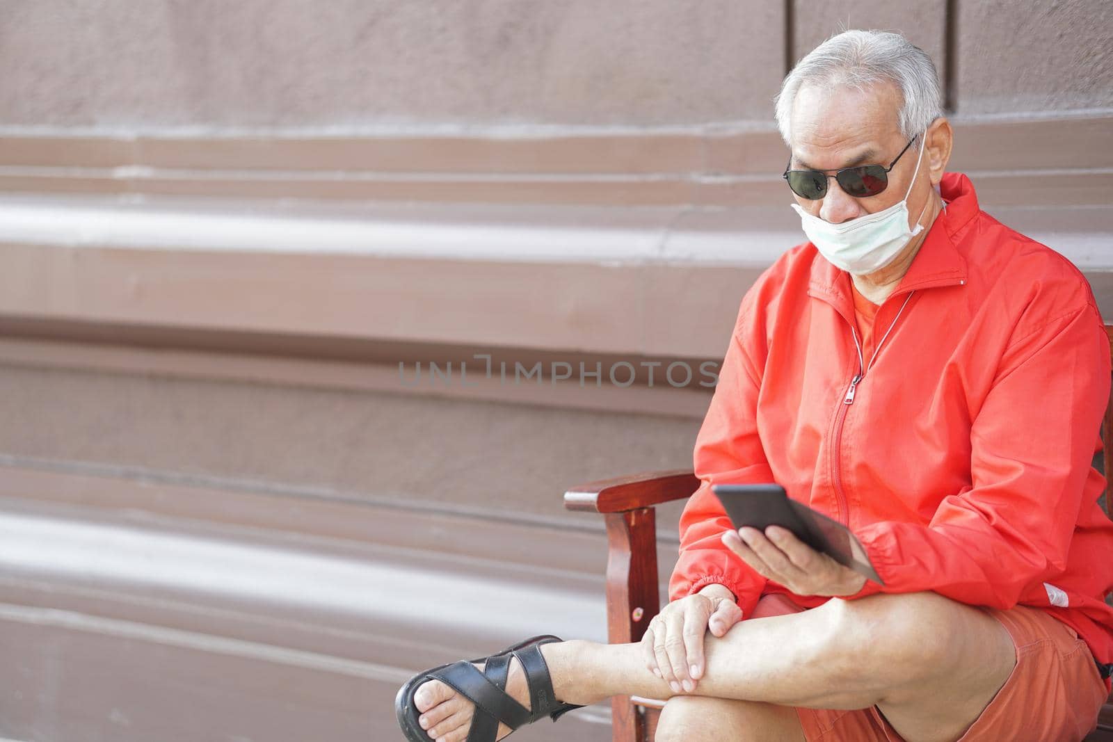 asian old elder senior man elderly male wearing face mask using mobile smart phone cellphone outdoor. mature retirement lifestyle