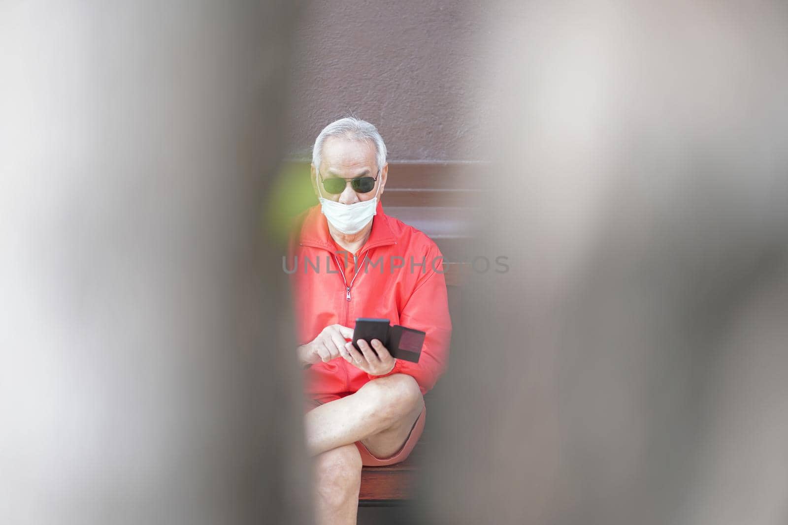 asian old elder senior man elderly male wearing face mask using mobile smart phone cellphone outdoor. mature retirement lifestyle