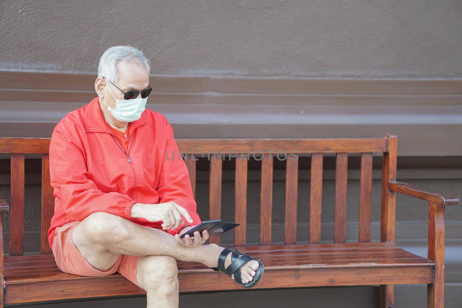 asian old elder senior man wearing face mask elderly using mobile smart phone cellphone. mature retirement lifestyle by pp99