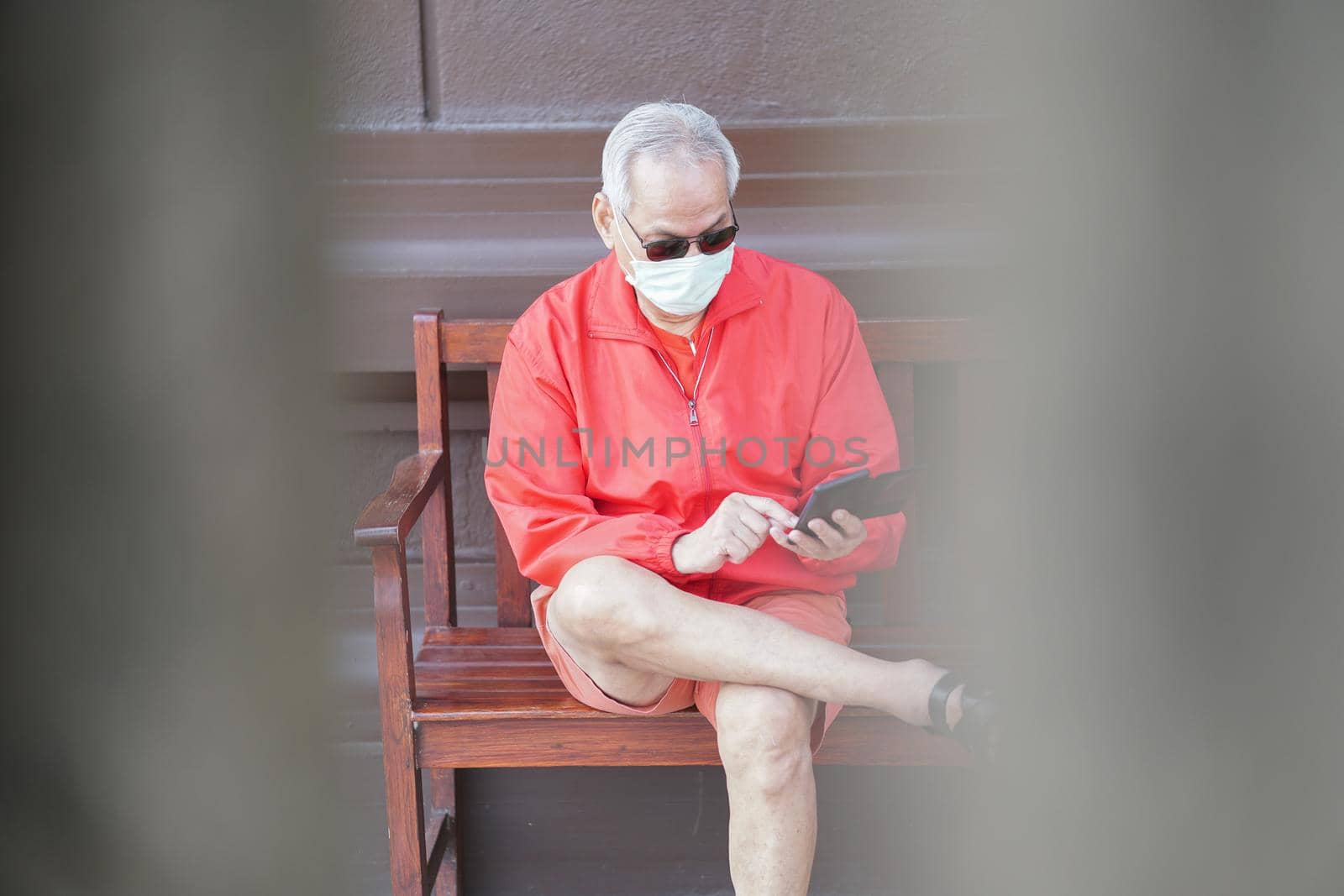 asian old elder senior man wearing face mask elderly using mobile smart phone cellphone. mature retirement lifestyle by pp99