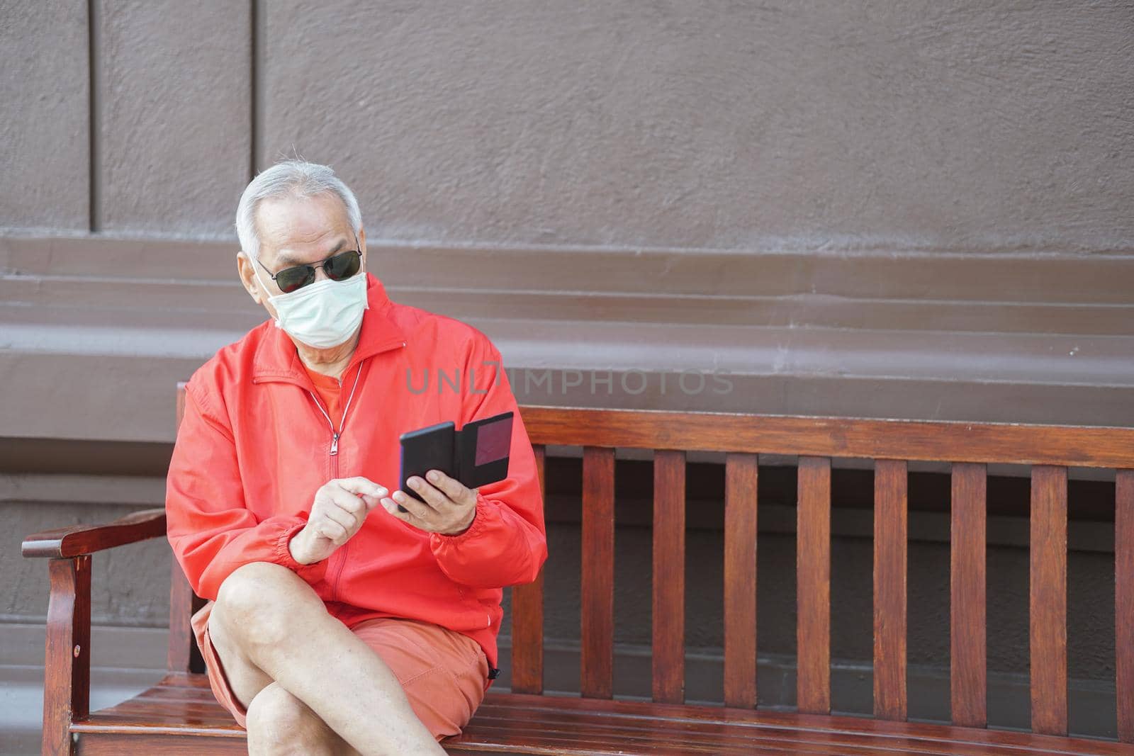 asian old elder senior man elderly male wearing face mask using mobile smart phone cellphone outdoor. mature retirement lifestyle