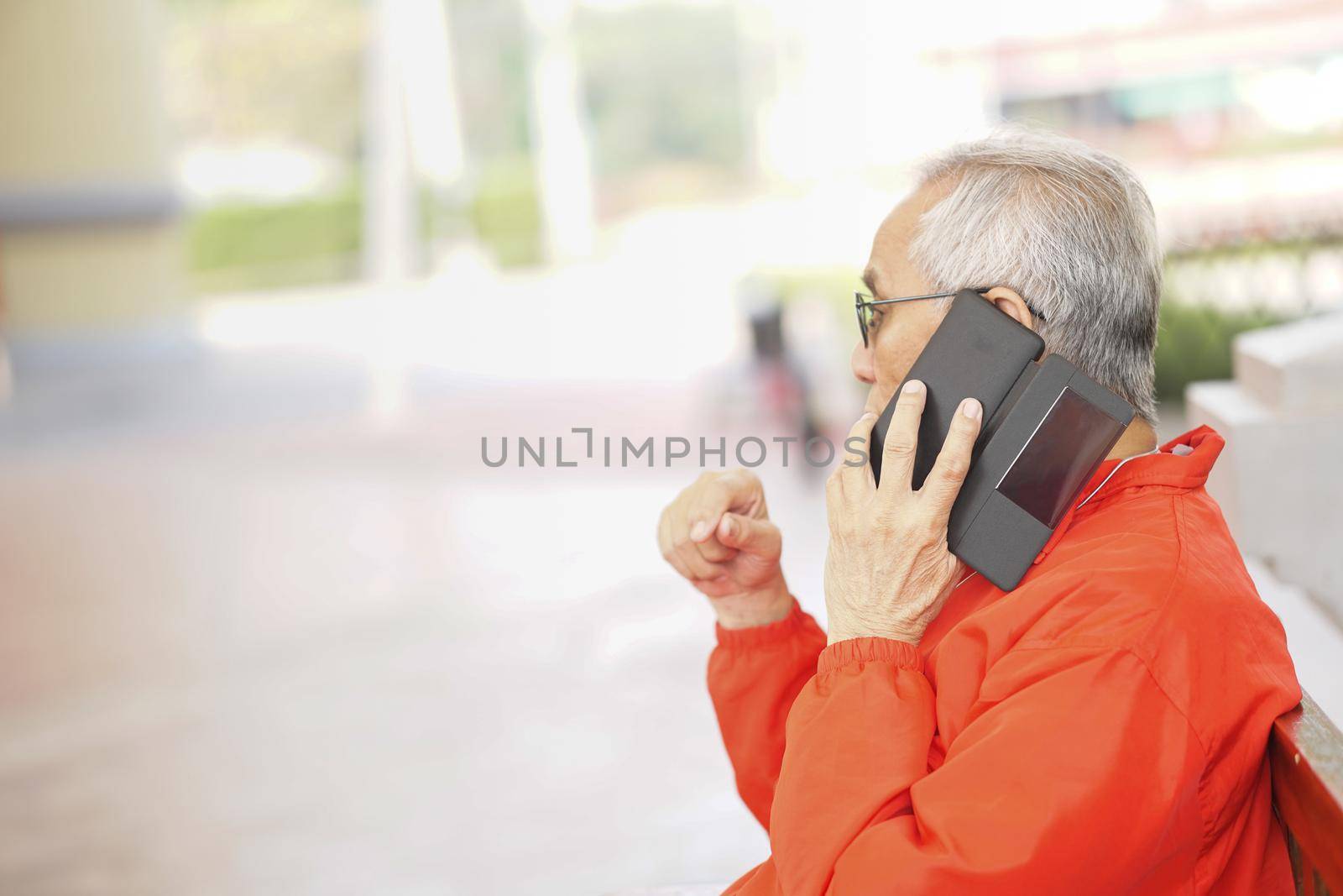 asian old asian elderly senior elder man talking on smart mobile phone outdoor