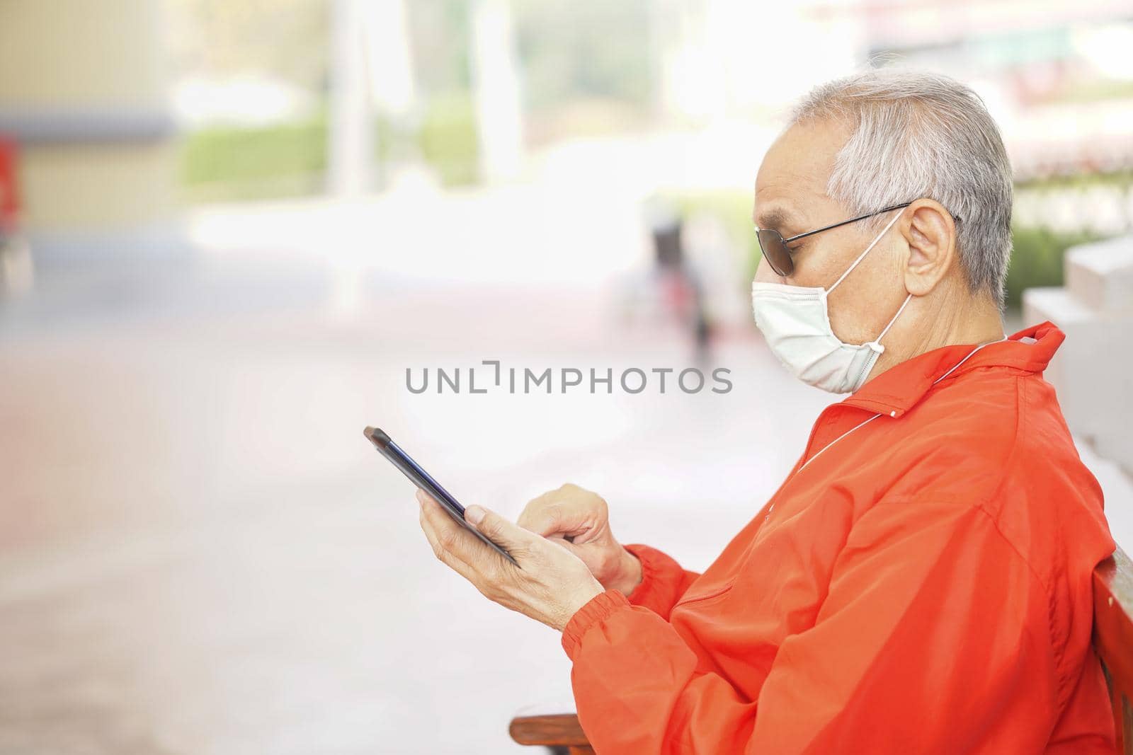 asian old elder senior man wearing face mask elderly using mobile smart phone cellphone. mature retirement lifestyle by pp99