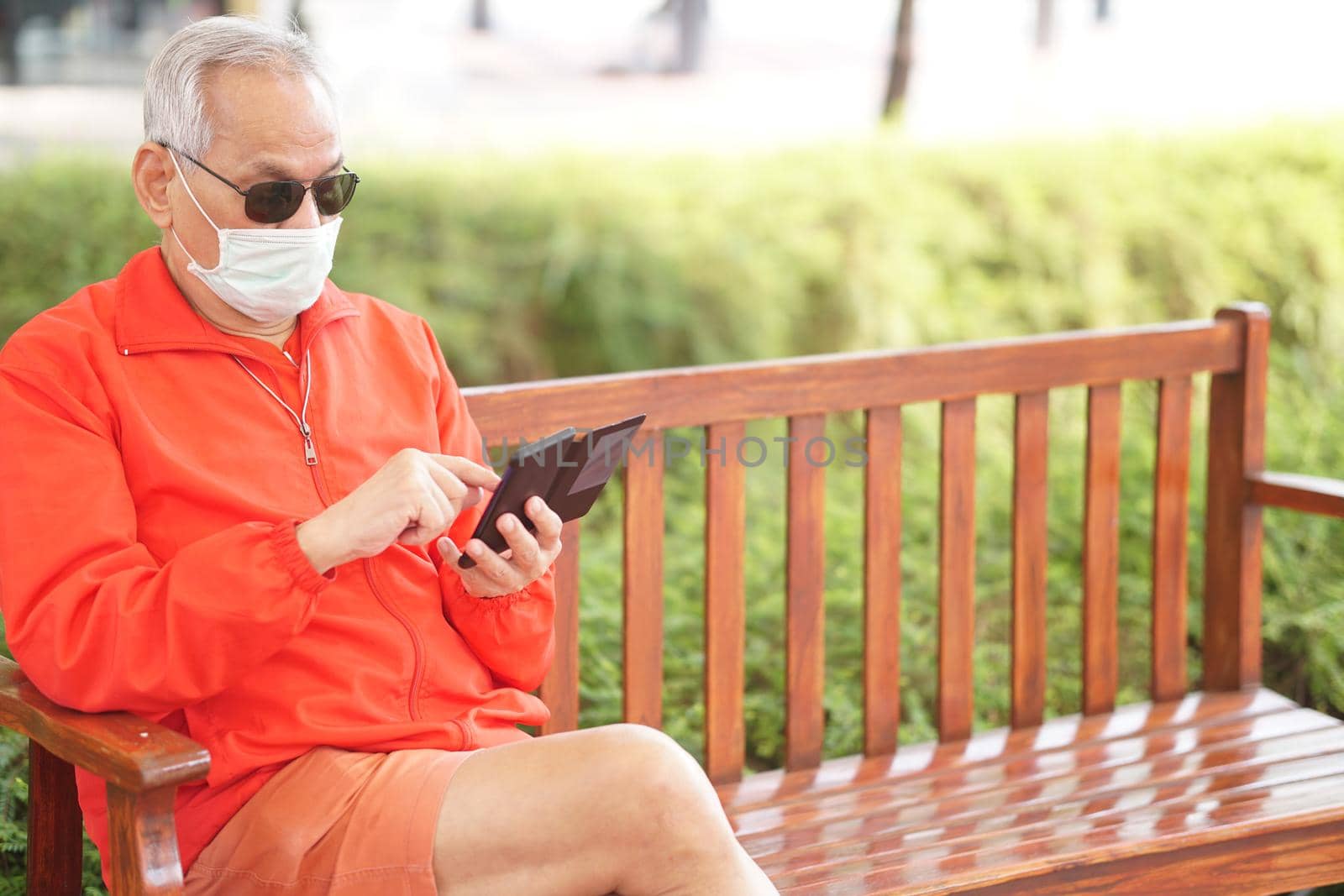 asian old elder senior man wearing face mask elderly using mobile smart phone cellphone. mature retirement lifestyle by pp99