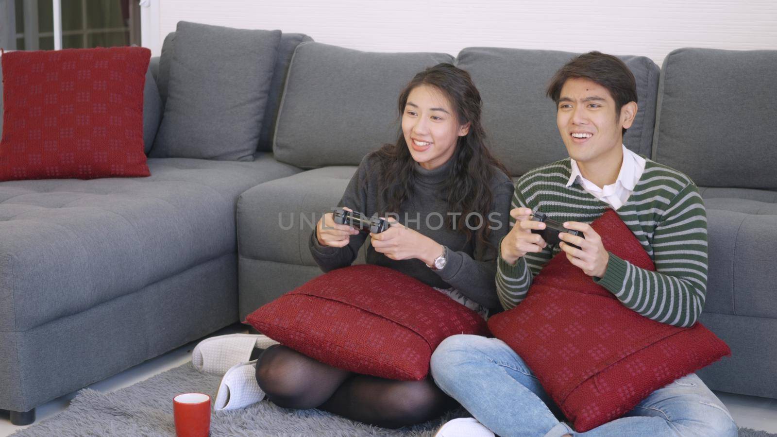 husband and wife smile and laugh enjoying funny with each other playing video game by Sorapop