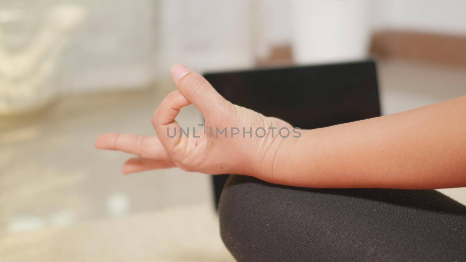 woman leggings practicing yoga at home sitting in lotus pose on yoga mat by Sorapop