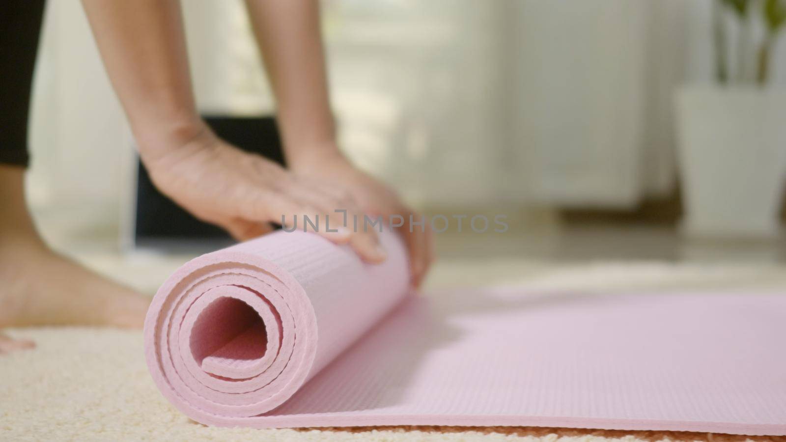 Asian young woman rolling fitness yoga pink mat after sport practice for exercise, female working out at home in living room. lifestyle sport healthy concept, slow motion from 60fps