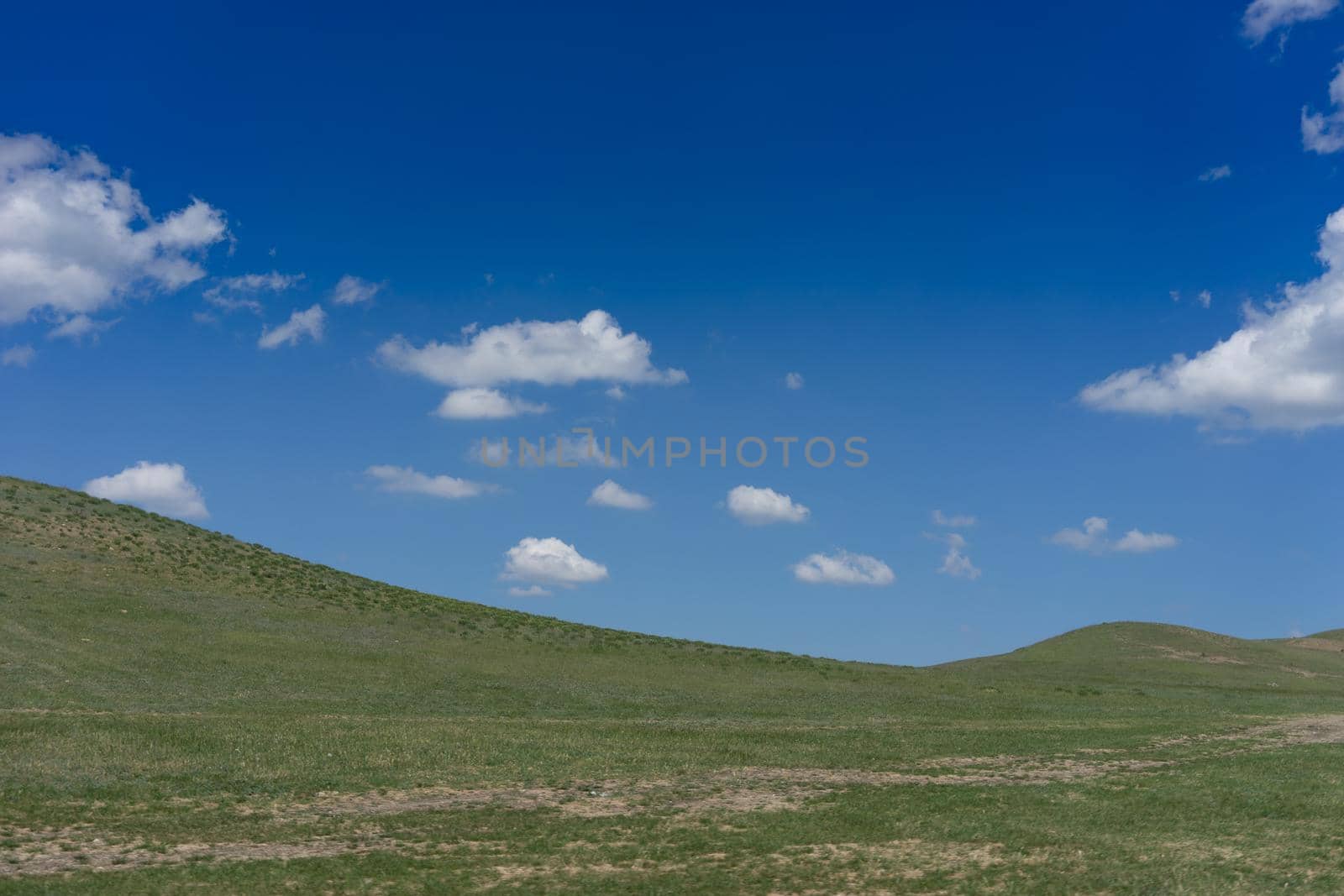 Natural landscape with hills against blue sky with white clouds.