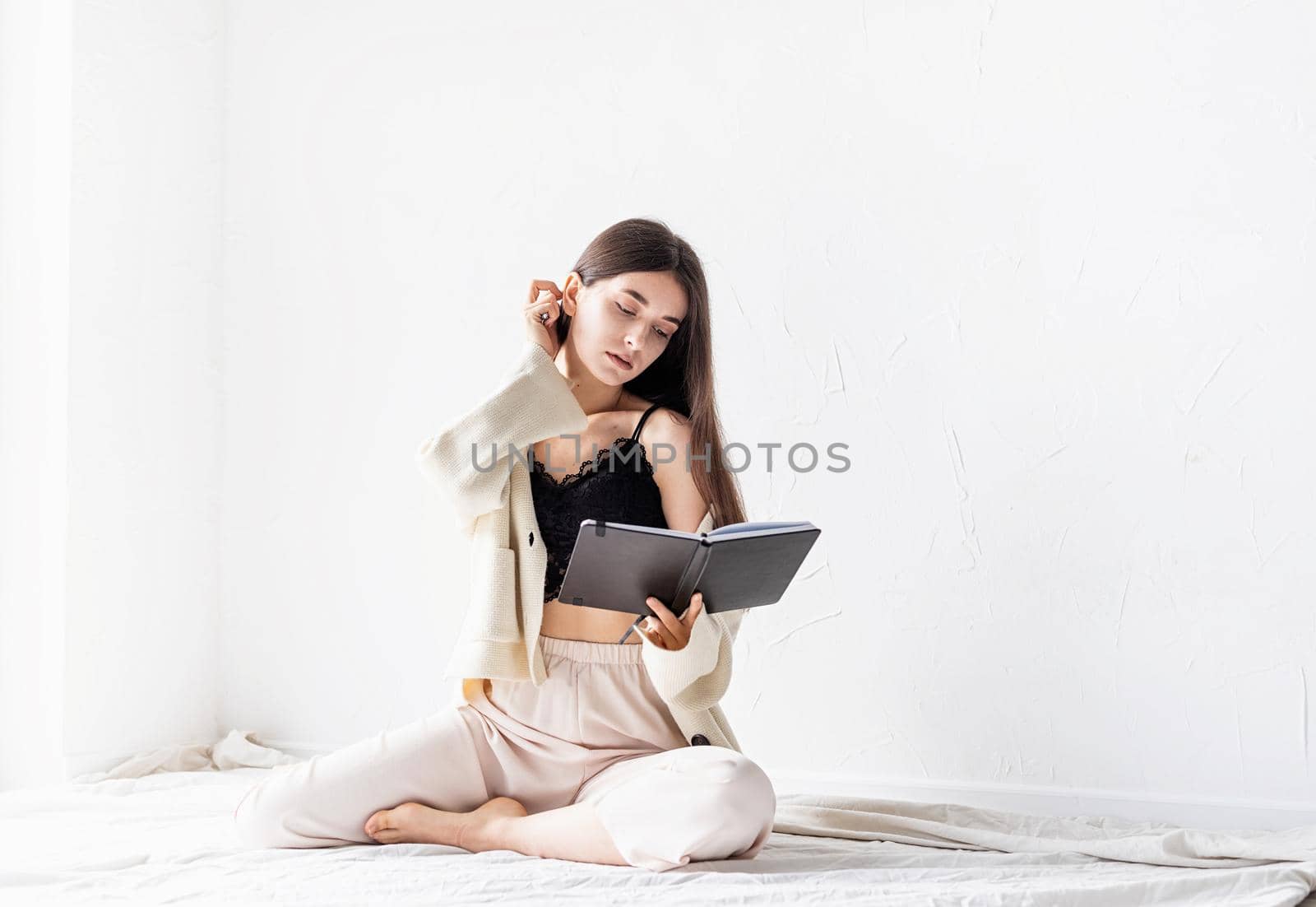 Beautiful sexy woman in comfy home clothes writing notes sitting on the floor, thinking