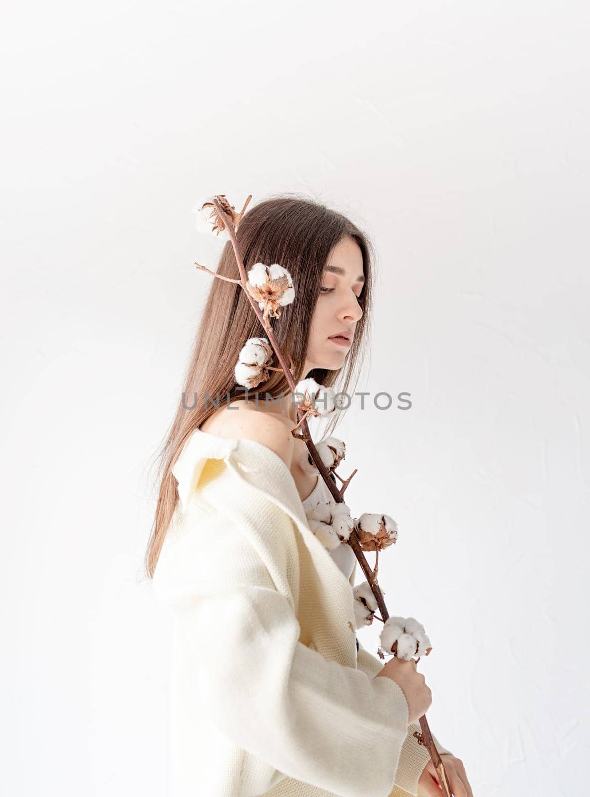 Beautiful woman in cozy clothes holding branch of cotton flowers by Desperada
