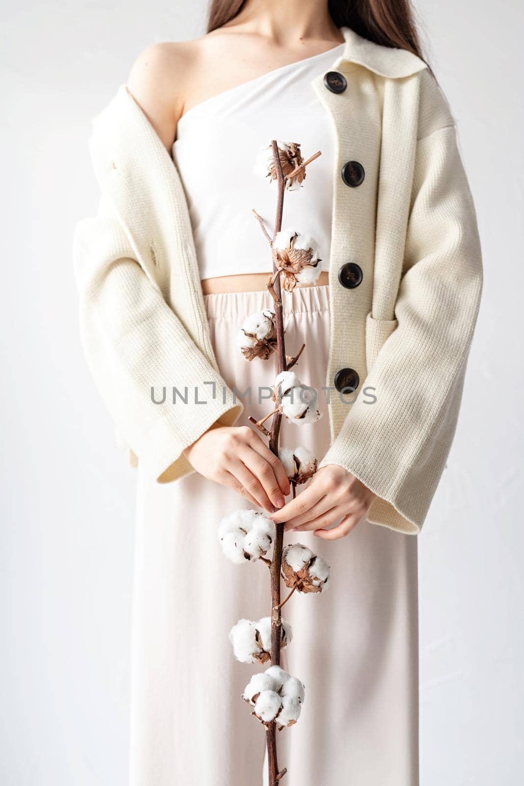Beautiful woman in cozy clothes holding branch of cotton flowers by Desperada
