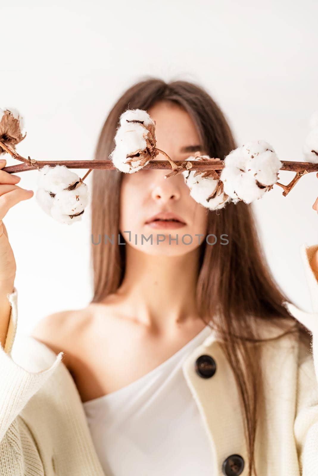 Beautiful woman in cozy clothes holding branch of cotton flowers by Desperada