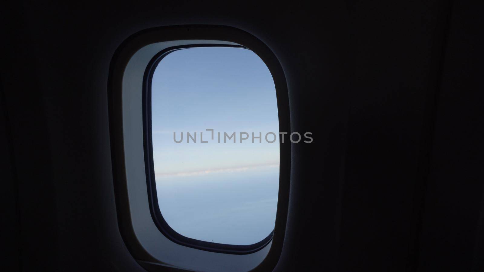 Clouds in the aircraft's porthole. Blue sky view from airplane window.