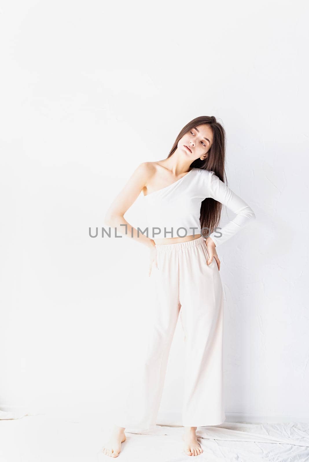 Young brunette woman in white clothes standing looking away by Desperada