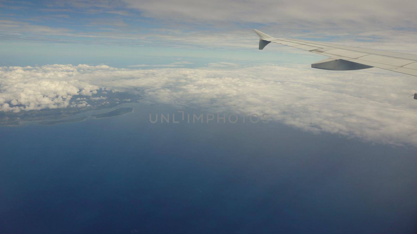 Blue sea or ocean in it and small tropical islands. Looking through window aircraft during flight