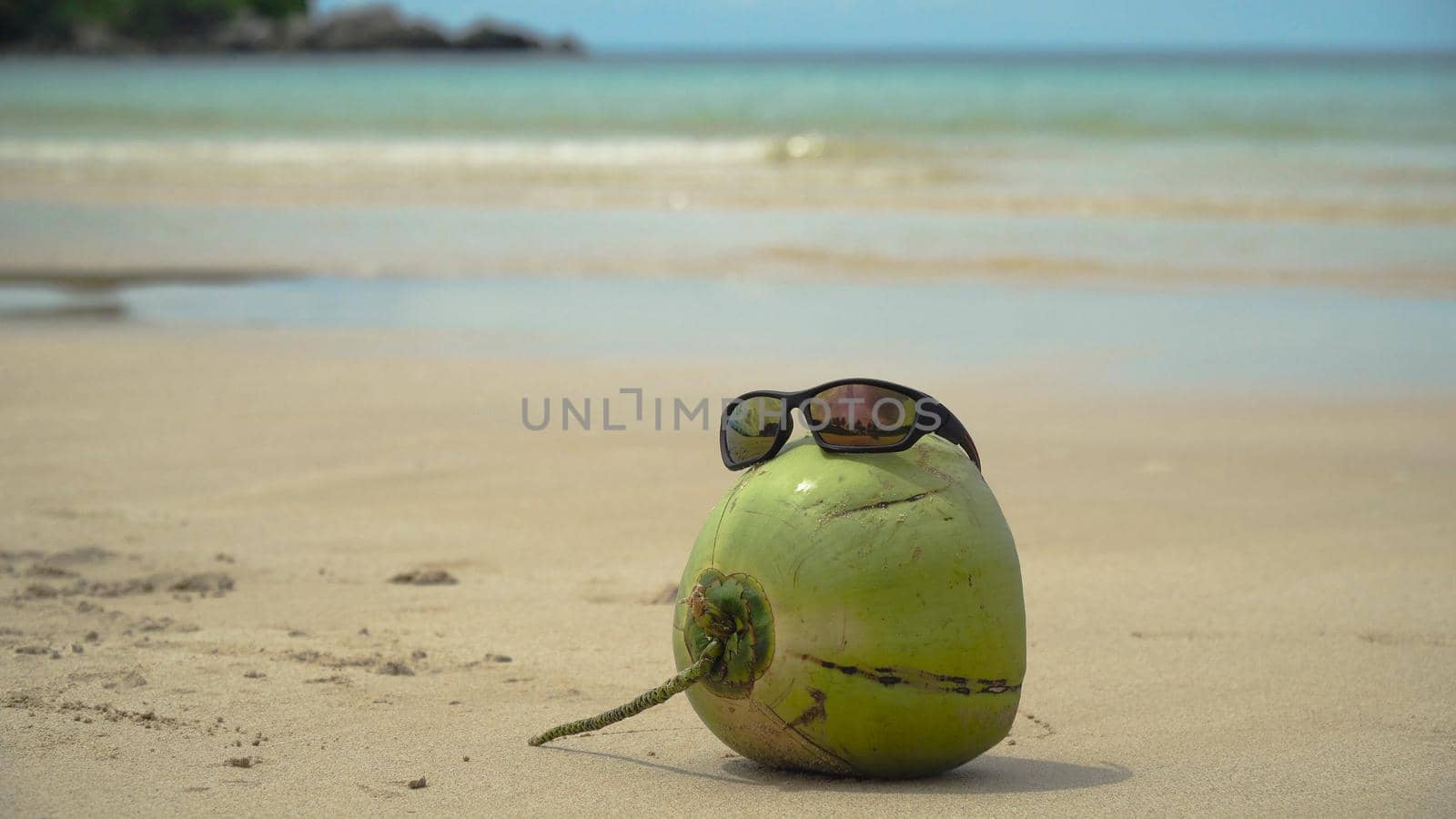 Green coconut on the sand of a tropical beach in sunglasses. Coconut funny wearing sunglasses on the beach. Fresh coconut from palm on a sandy beach. Philippines , El Nido. Travel concept.