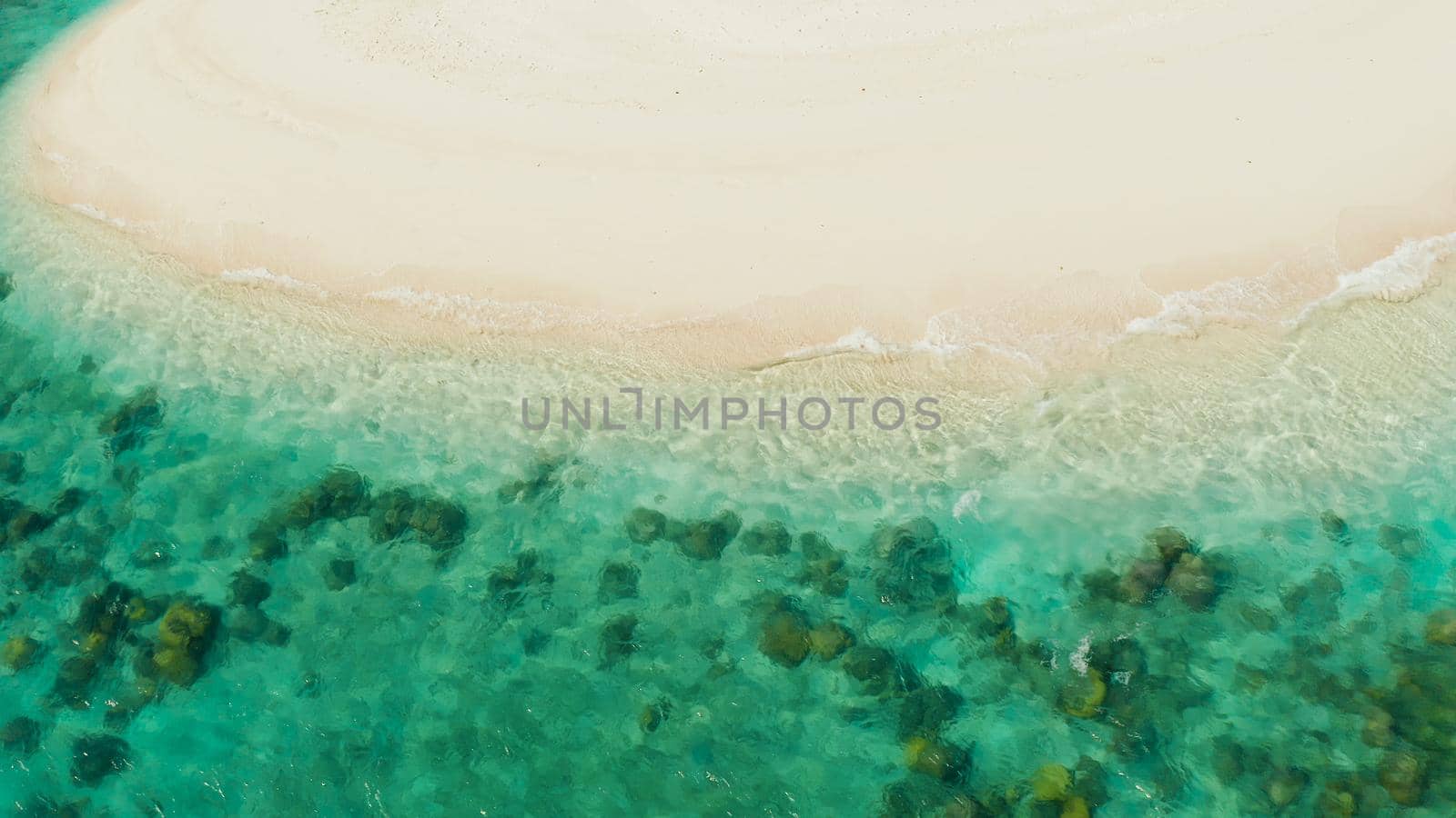 Sandy beach with and azure water of the lagoon,copy space for text, top view. Sea water surface in lagoon. Transparent turquoise ocean water surface. Background texture
