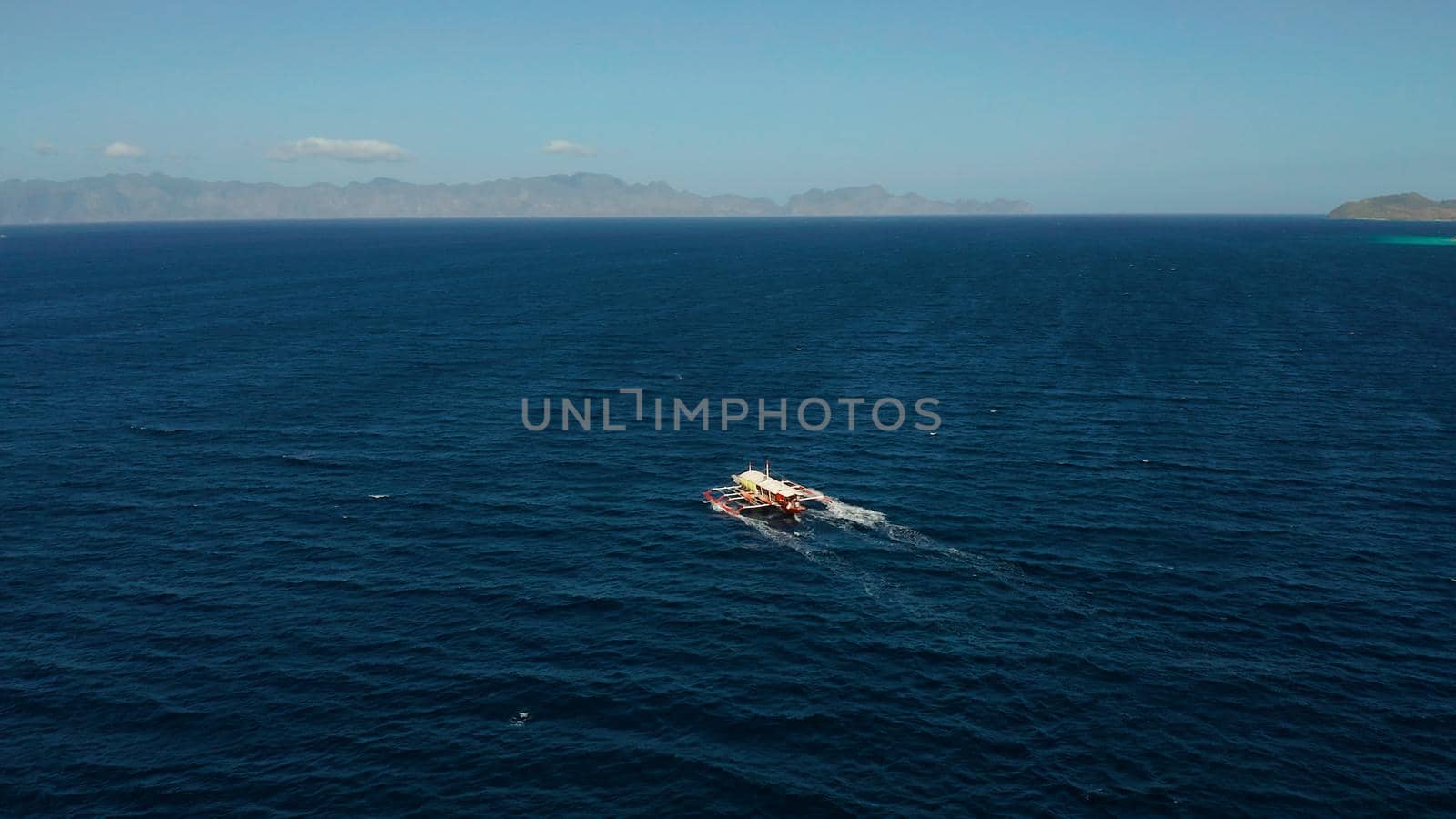 Aerial view tour boat in sea. Seascape blue sea and tropical islands. traditional Filipino wooden outrigger boat called a banca . Motorboat crossing ocean. Banca boat in the Philippines Palawan
