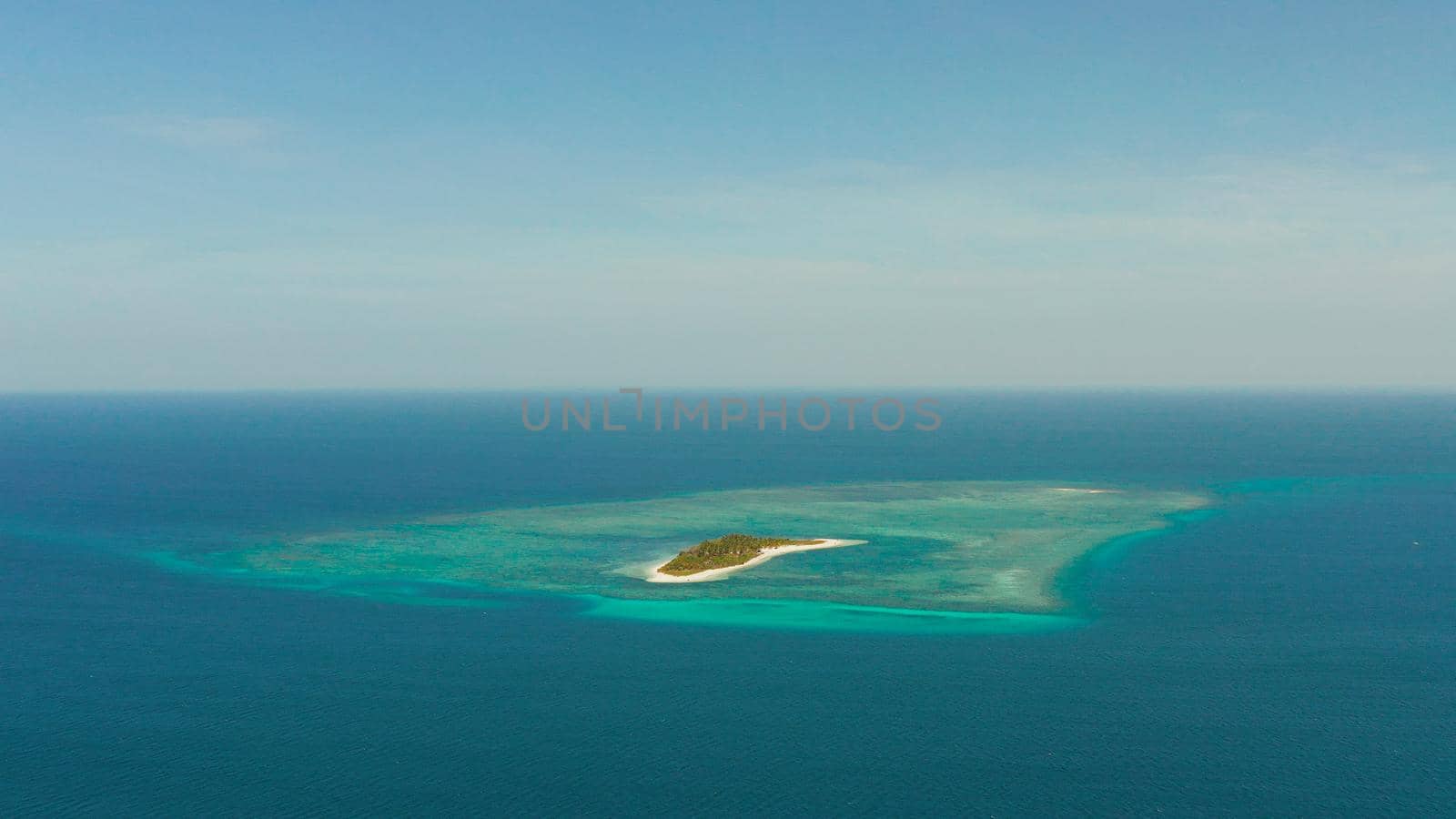 Small tropical island in the blue sea with a coral reef and the beach, top view. Summer and travel vacation concept. Canimeran Island, Balabac, Palawan, Philippines.